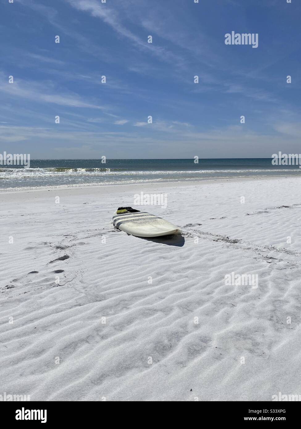 Surfboard on white sand beach with view of emerald water of the Gulf of Mexico - Smartphone Captured Stock Image