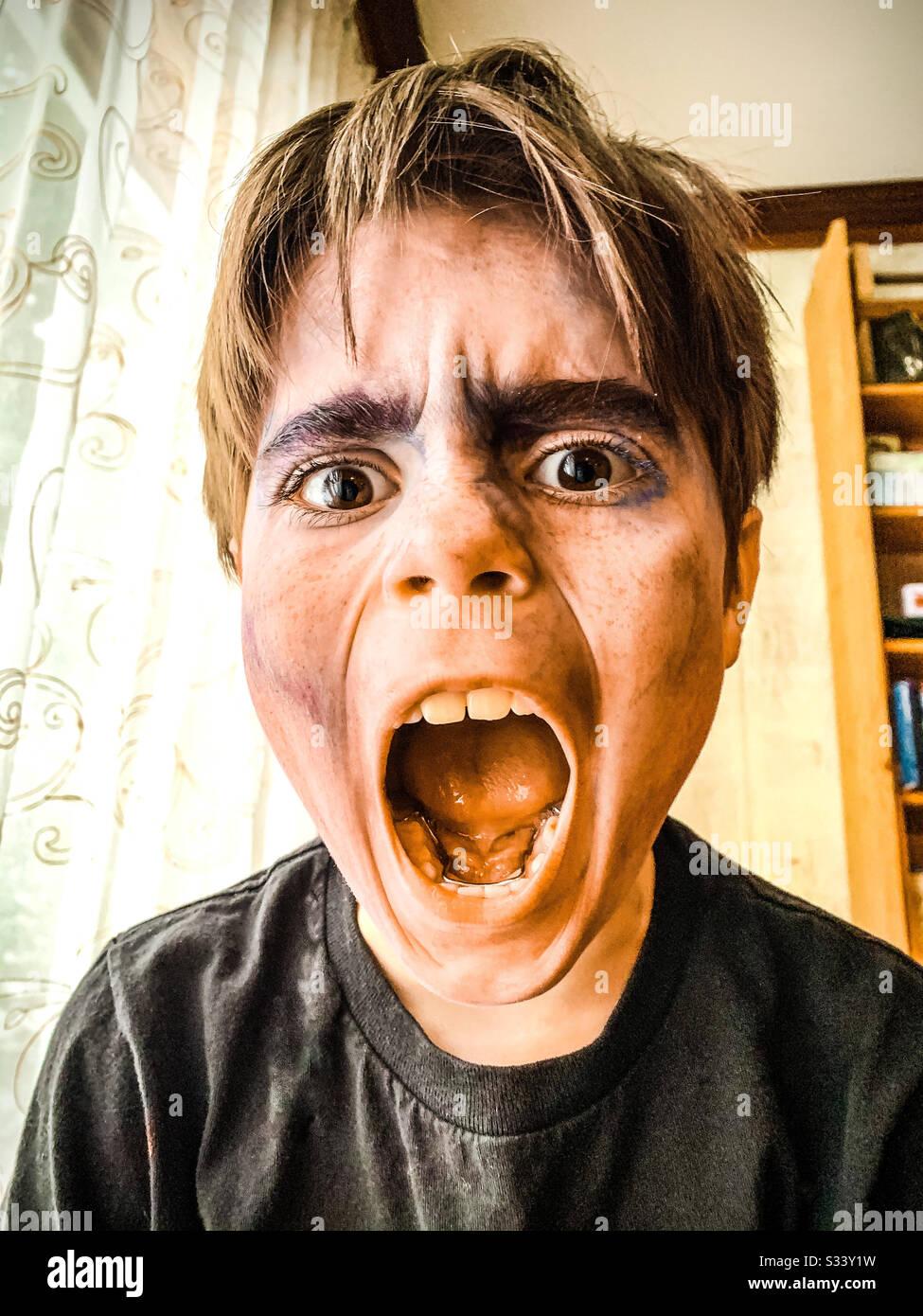 A ten year old boy with movie makeup on screaming at the camera. - Smartphone Captured Stock Image