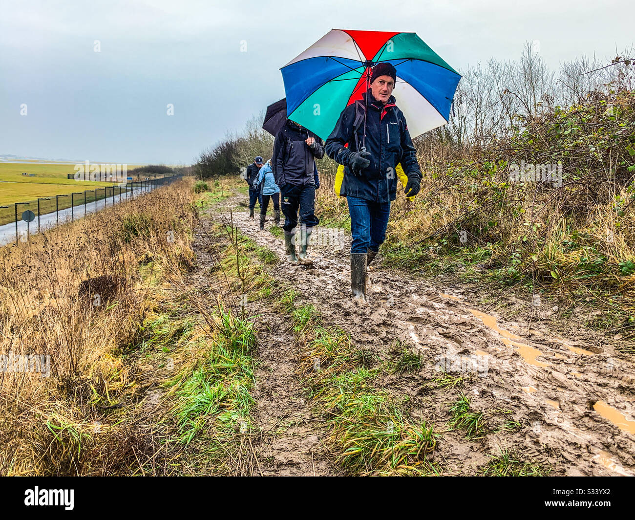 Ramblers walking in muddy fields near Manchester Airport Stock Photo