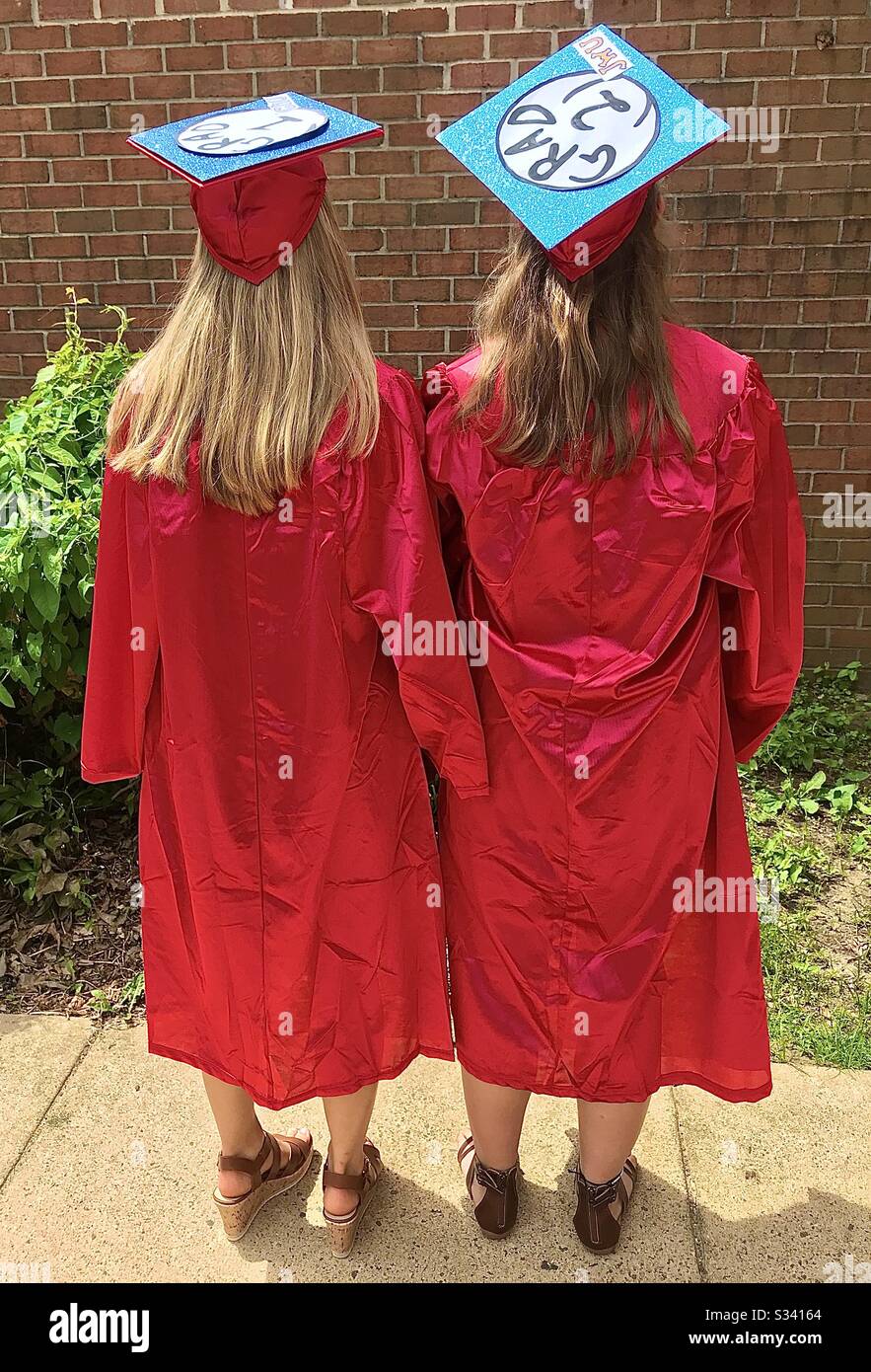 High school graduates in red cap and gown Stock Photo