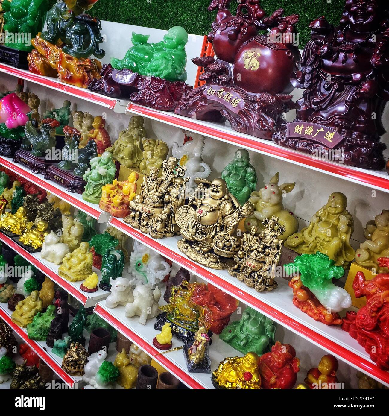 Laughing Buddhas and other ornaments for good luck for sale in a souvenir shop in Jalan Alor, a hawker food market in Bukit Bintang, Kuala Lumpur, Malaysia Stock Photo