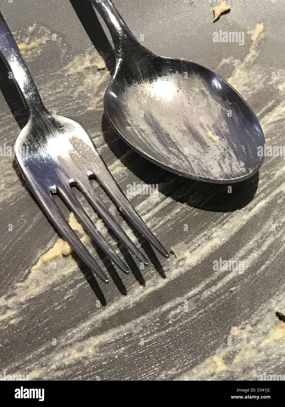 Fork and spoon on an empty dish after eating - Smartphone Captured Stock Image