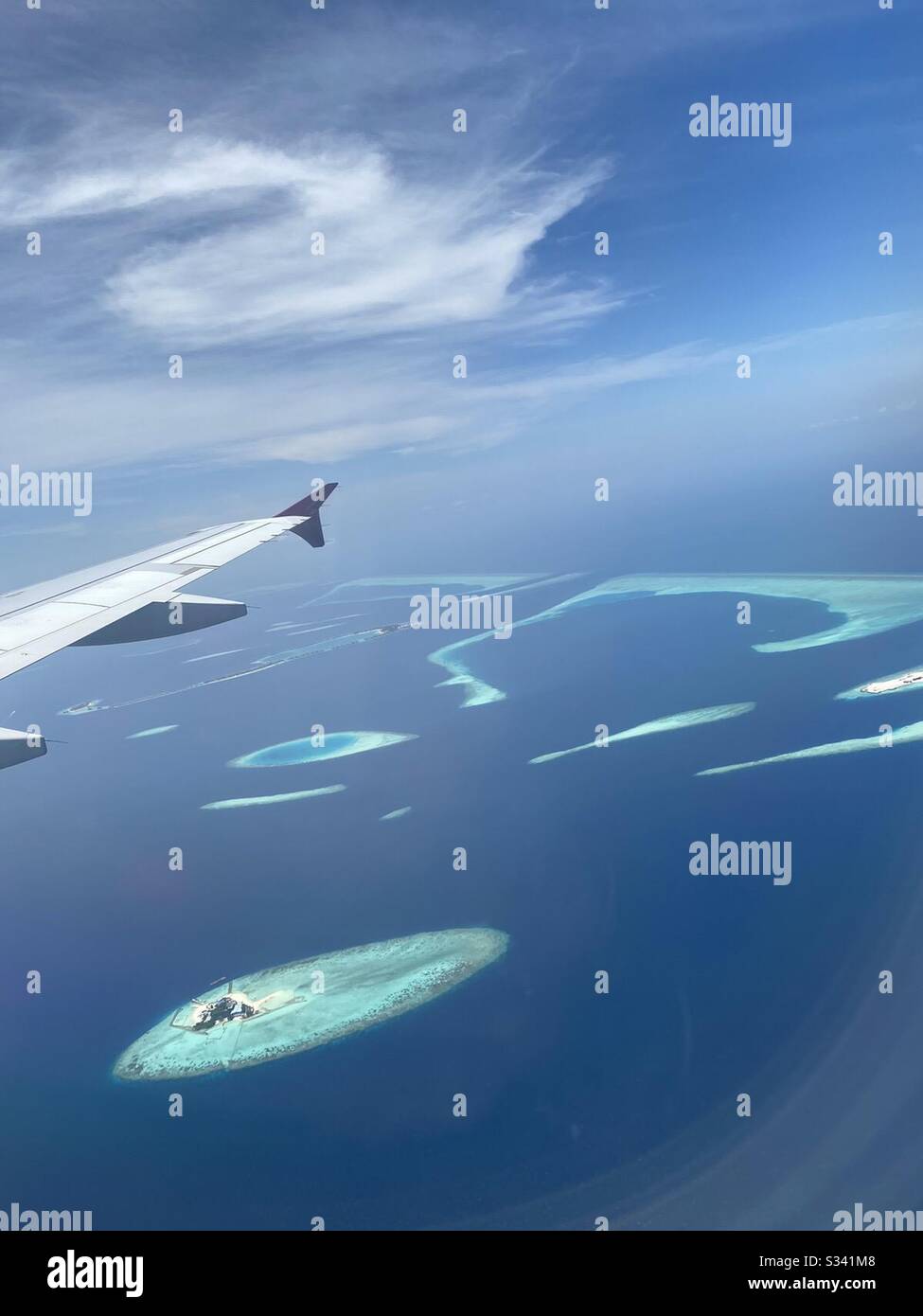 Aerial view of the Maldives islands atolls and turquoise water as seen from plane window. - Smartphone Captured Stock Image