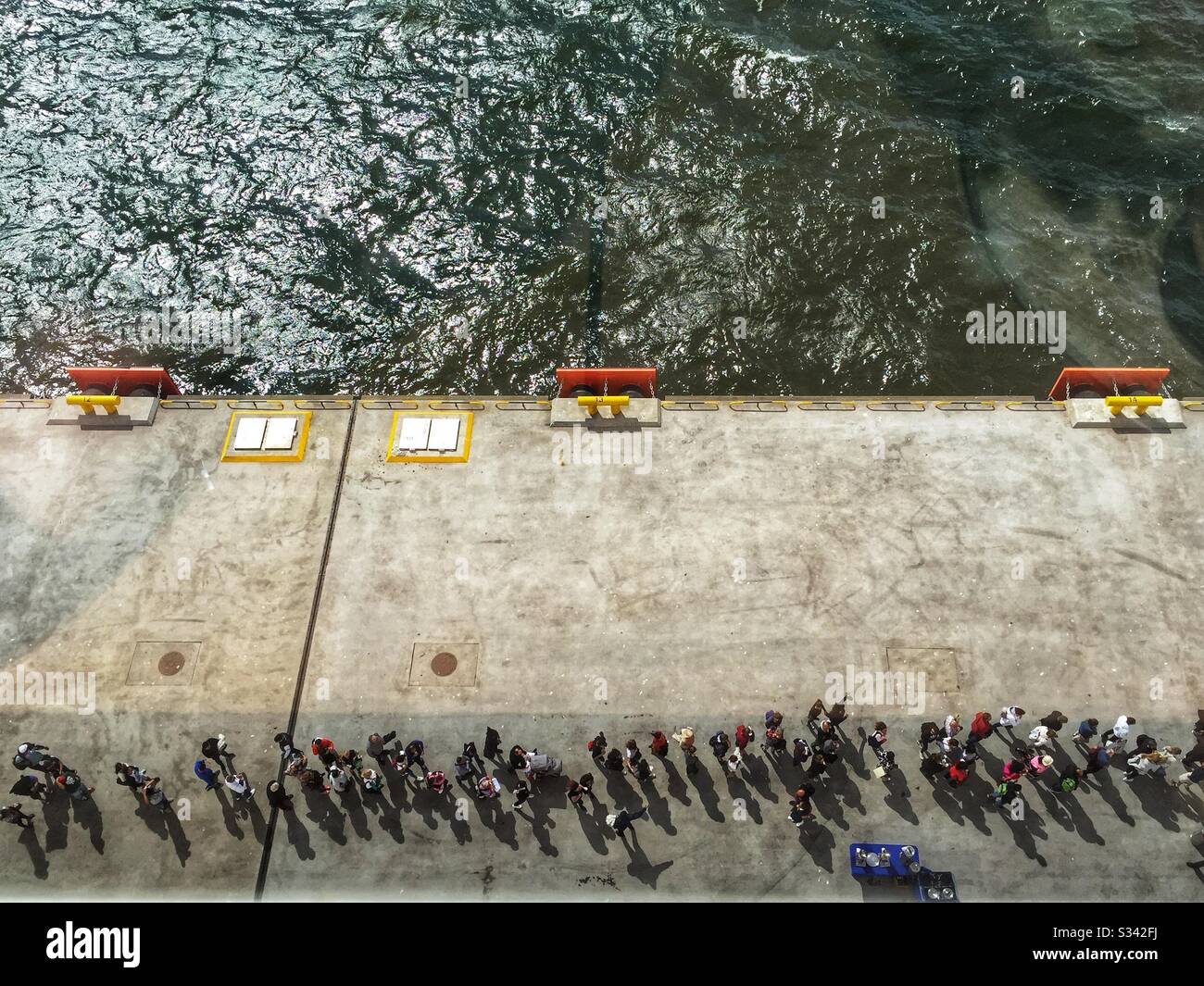 Looking down on large line of cruise ship passengers waiting to board ship. Stock Photo