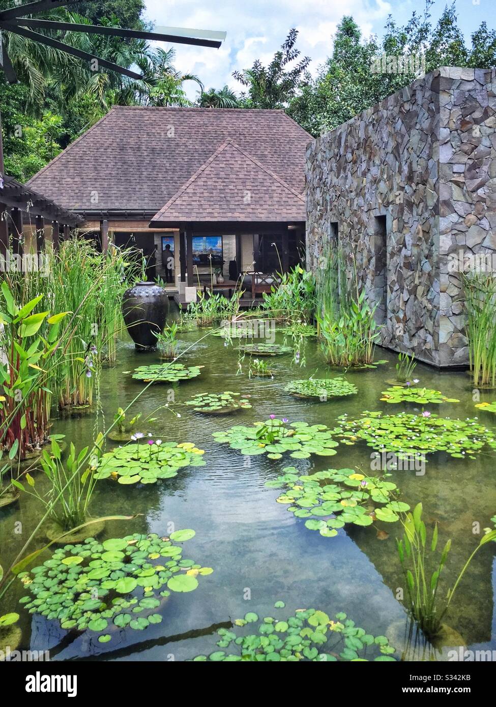 Ponds, water features, aquatic plants and giant cooling fans are a feature of the landscaping at The Banjaran Hotsprings Retreat near Ipoh, Malaysia Stock Photo