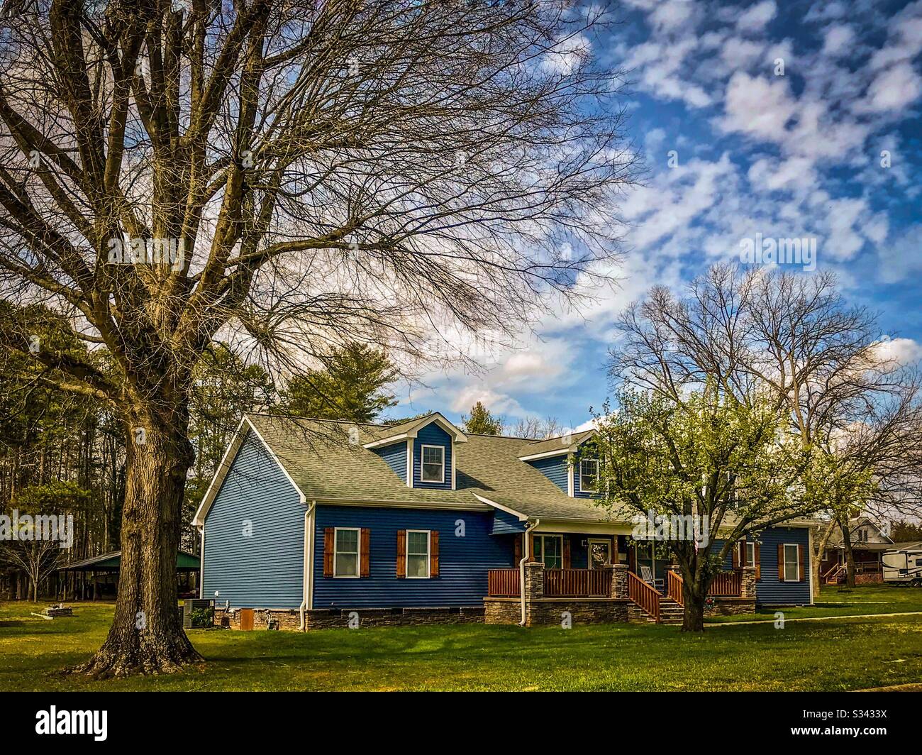 Blue house with rustic brown shutters and trim in early spring - Smartphone Captured Stock Image