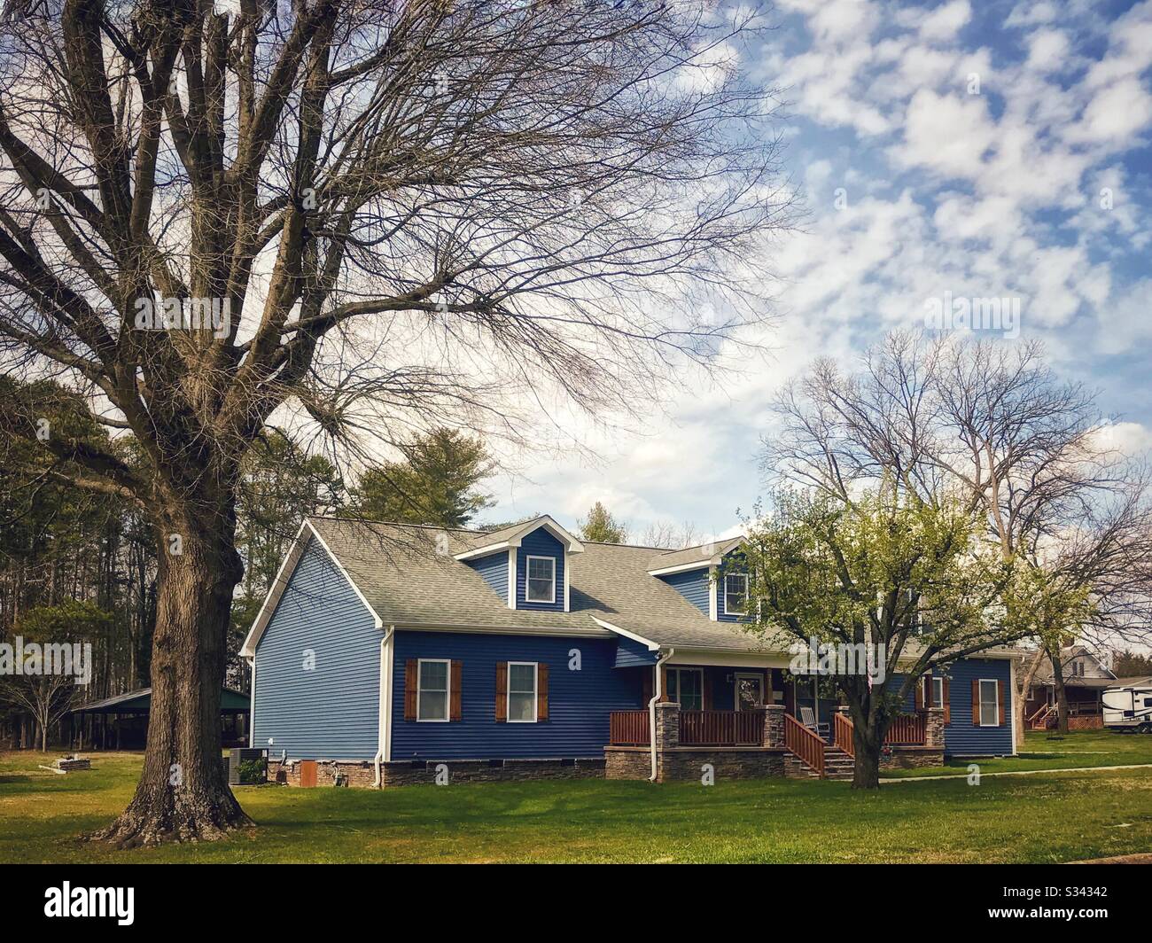 New blue home with rustic brown shutters and trim in early spring - Smartphone Captured Stock Image