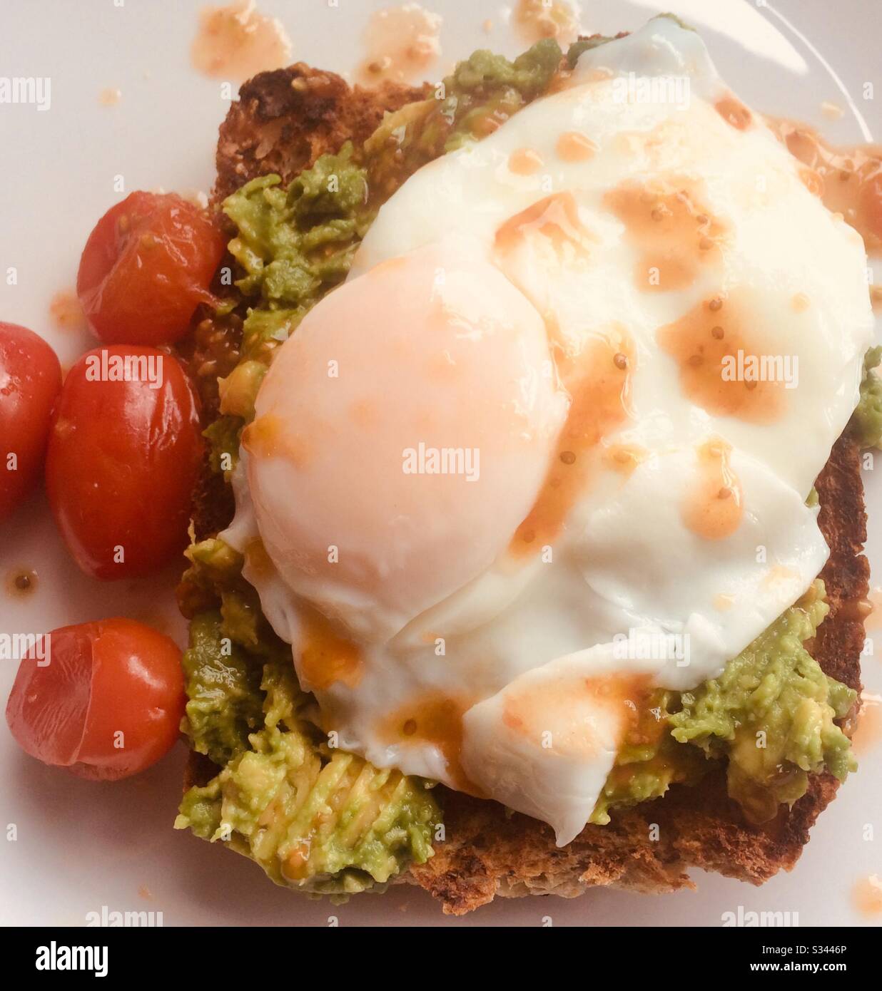 Poached egg and avocado on toast with cherry tomatoes - Smartphone Captured Stock Image