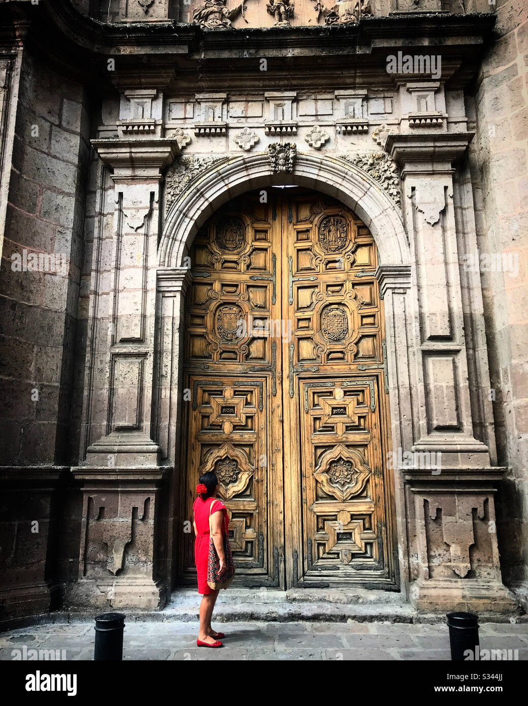 A Mexican woman dressed in a traditional red dress visits the church of Santa Rosa de Lima in Morelia, Michoacan, Mexico Stock Photo