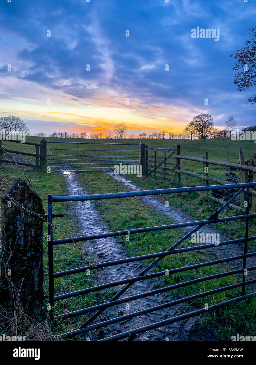 Sunset overlooking fields, gates and fences Stock Photo