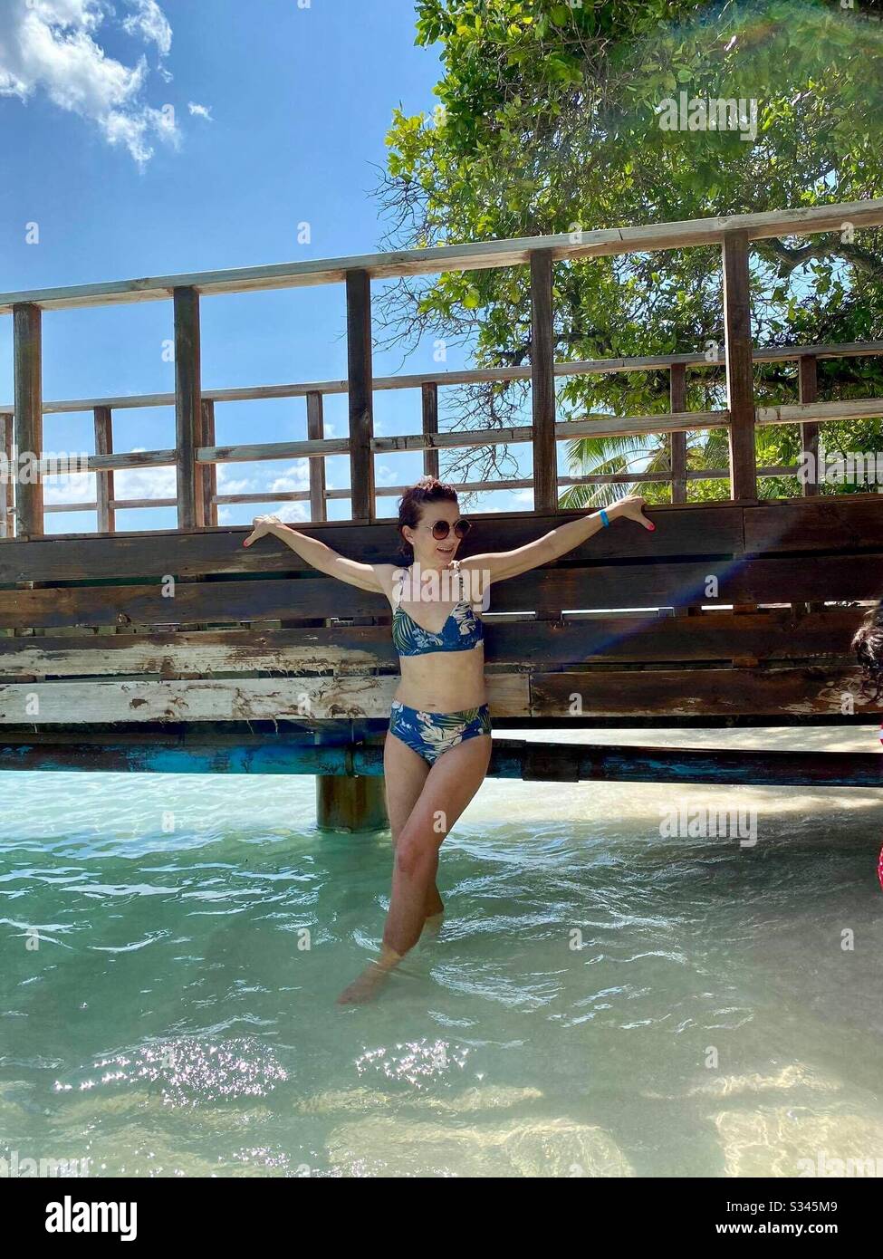 Tourist woman wearing bikini by wooden pier on tropical beach in the Maldives Stock Photo