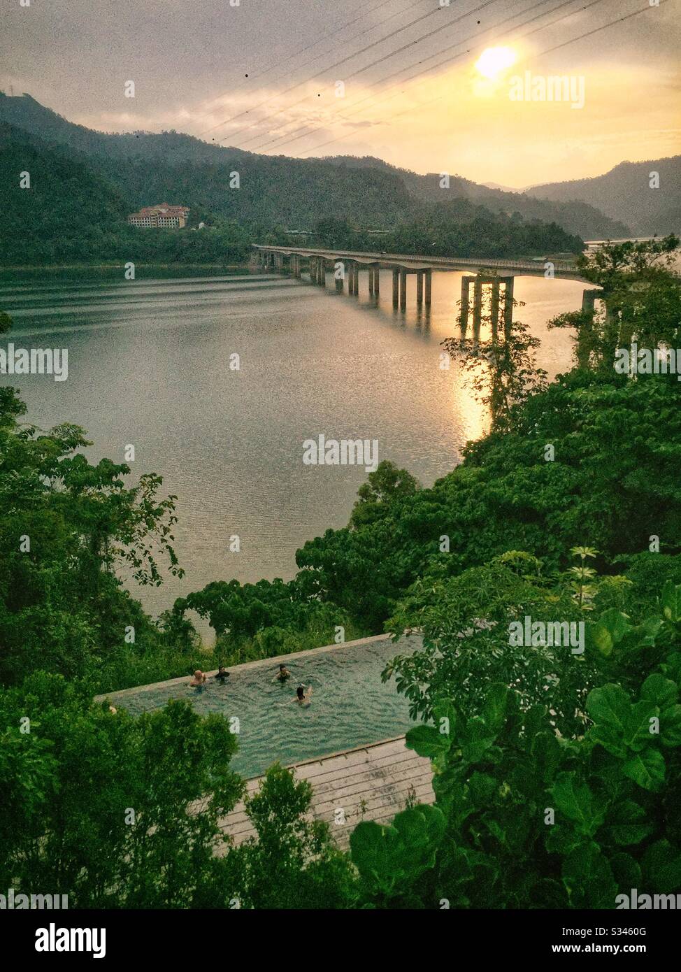 Guests enjoy the swimming pool at sunset, Belum Rainforest Resort, Pulau Banding (Banding Island), Perak, Malaysia - Smartphone Captured Stock Image