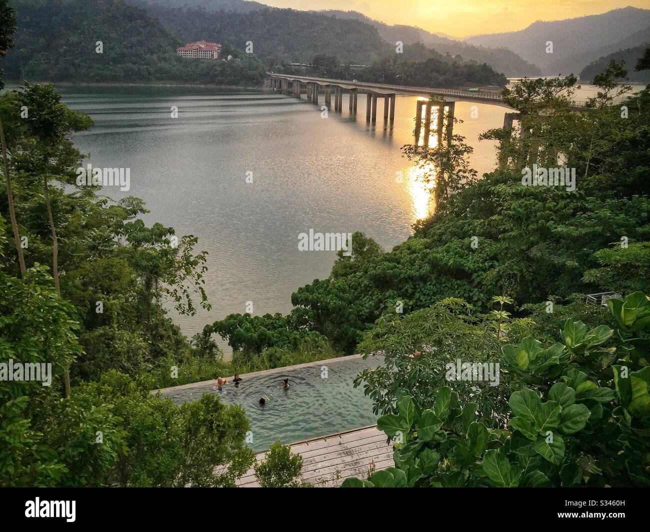 Guests enjoy the swimming pool at sunset, Belum Rainforest Resort, Pulau Banding (Banding Island), Perak, Malaysia - Smartphone Captured Stock Image