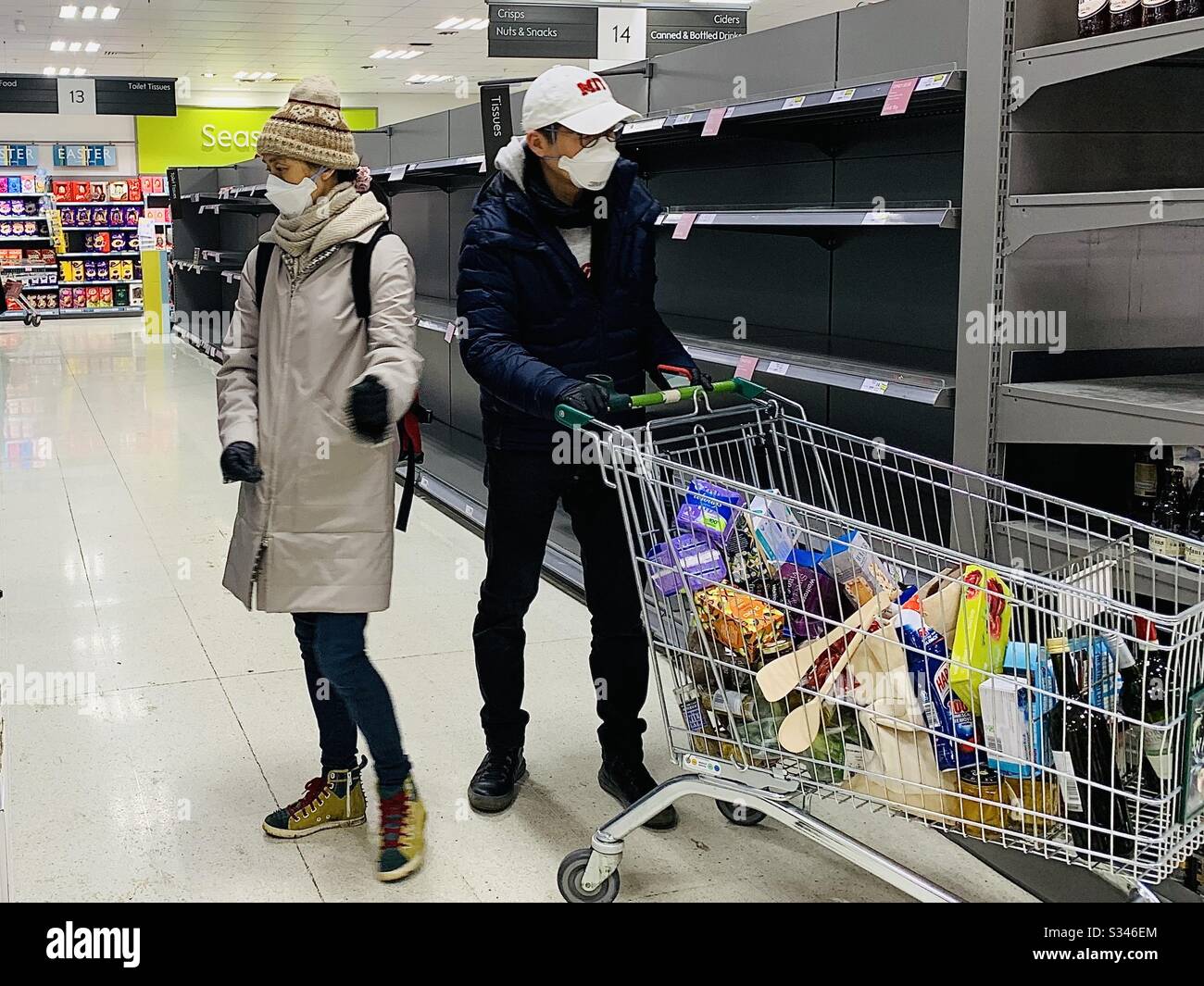 A couple wearing face masks look at empty shelves in Waitrose Oxford