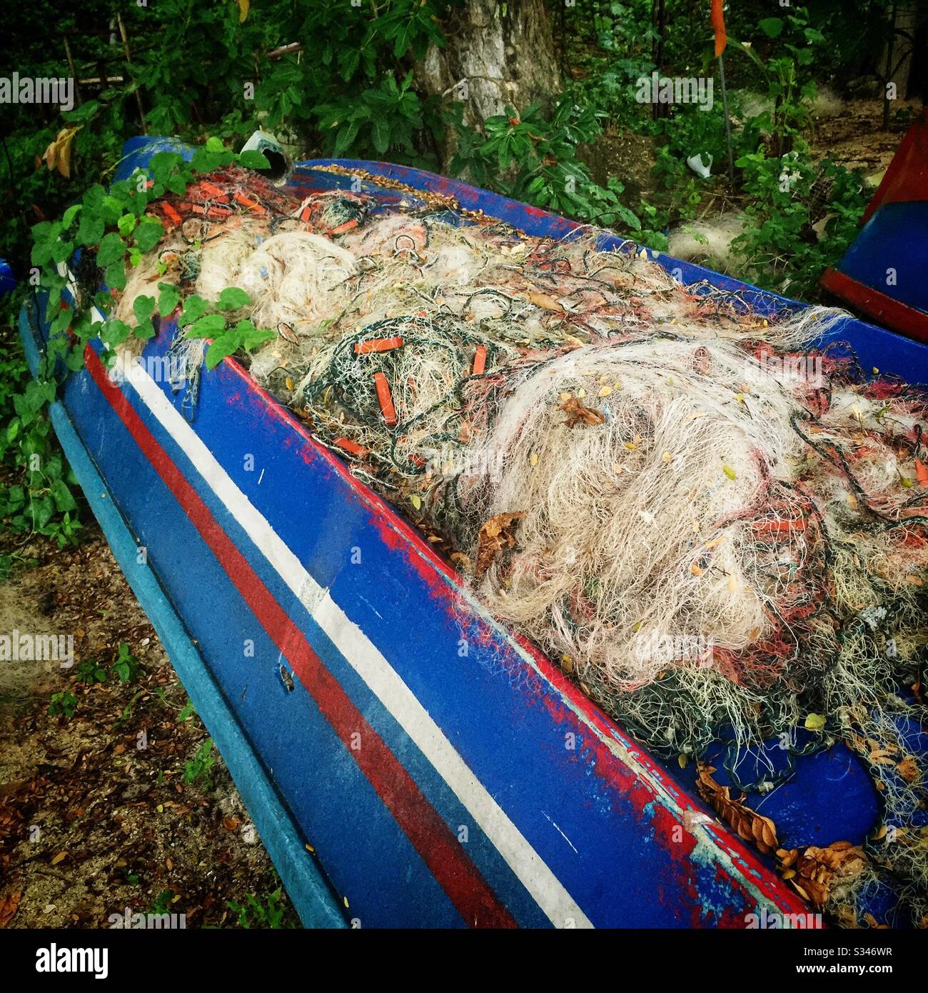 A tangle of disused nets on an upturned traditional fishing boat by the beach at Batu Ferringhi, Penang, Malaysia - Smartphone Captured Stock Image