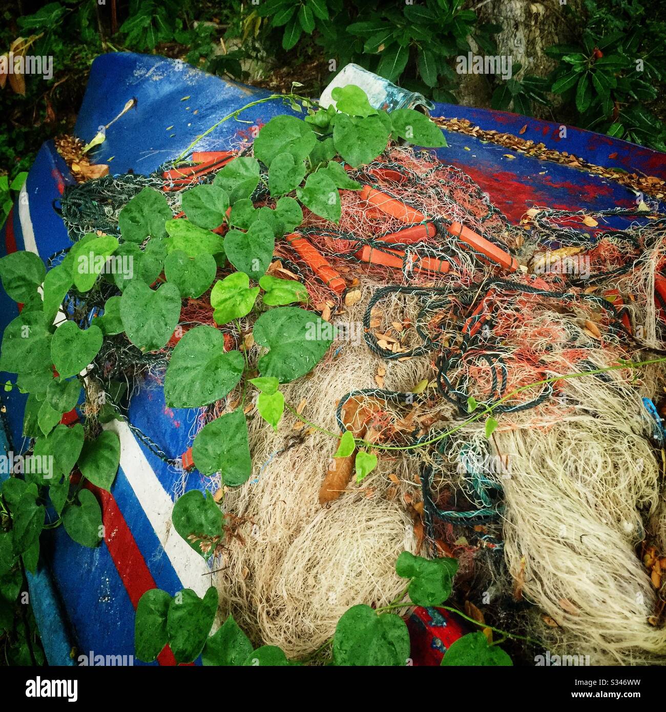 A tangle of disused nets on an upturned traditional fishing boat by the beach at Batu Ferringhi, Penang, Malaysia - Smartphone Captured Stock Image