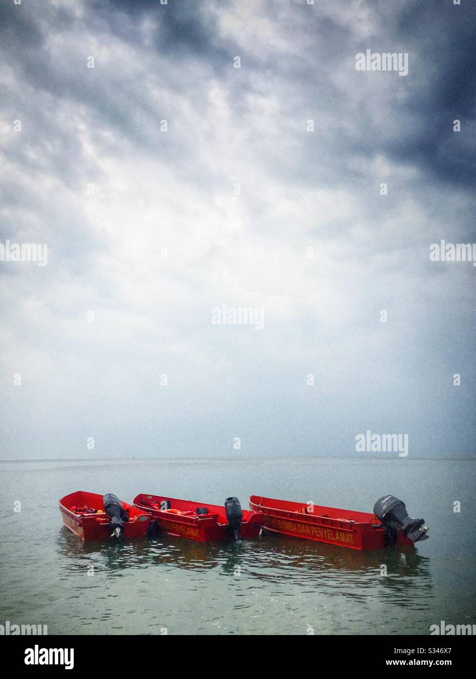Fire And Rescue boats moored of the beach under a clearing sky after morning rain squall, Batu Ferringhi, Penang, Malaysia - Smartphone Captured Stock Image