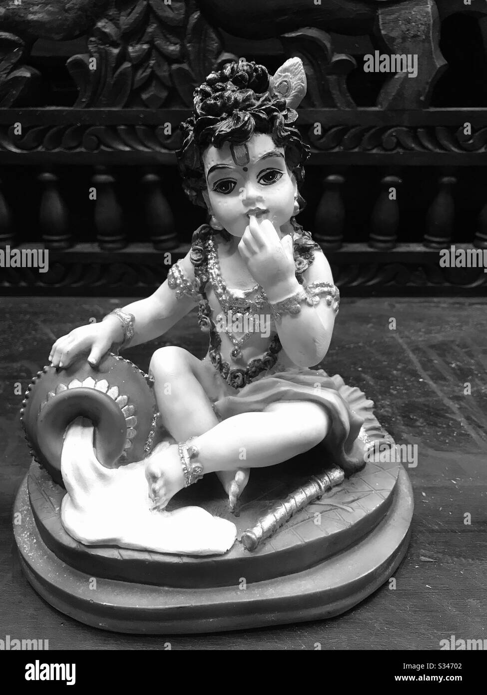Baby Krishna eating butter- cute small wax statue found In a handicrafts shop in Little India Arcade, Singapore-Hindu God Sri Krishna-Janmashtami-Lord shri Krishnan - Soulful Love of God-black & white Stock Photo