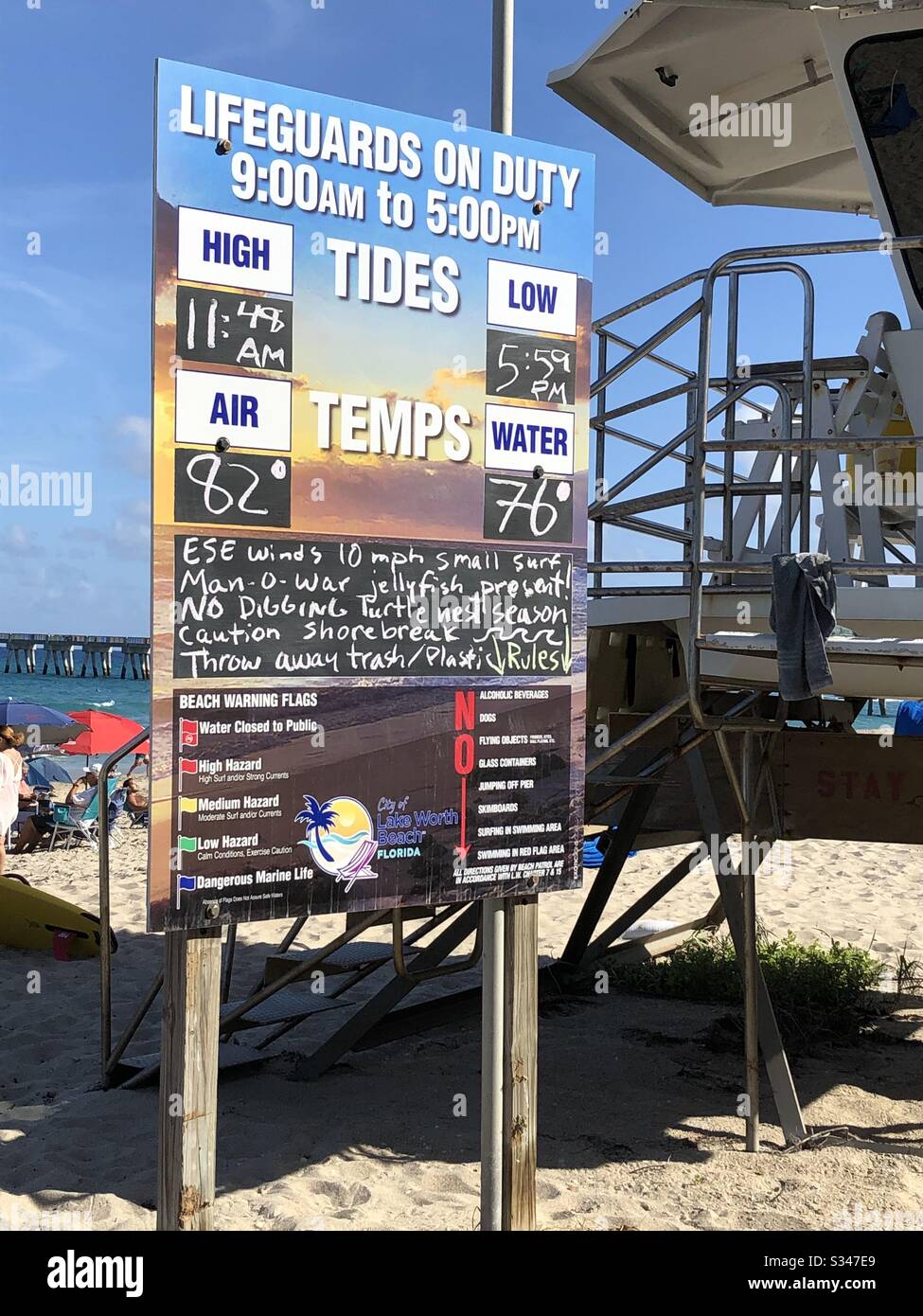 Sign by the lifeguard station showing the tides, air and water temperature at Lake Worth Beach, March 2020. - Smartphone Captured Stock Image