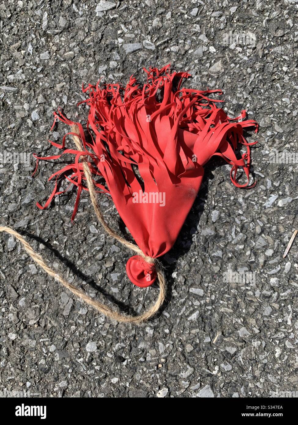 Red balloon popped on ground Stock Photo - Alamy