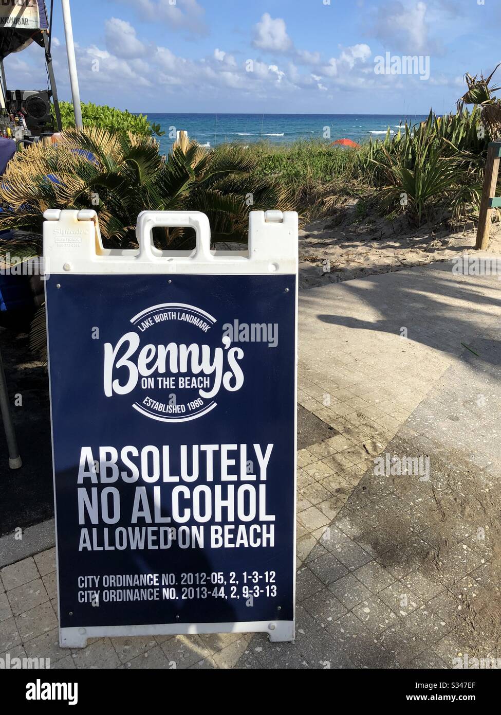 Landmark sign for Benny’s on the Beach warning “absolutely no alcohol allowed on the beach” at Lake Worth Beach and pier, Florida. - Smartphone Captured Stock Image