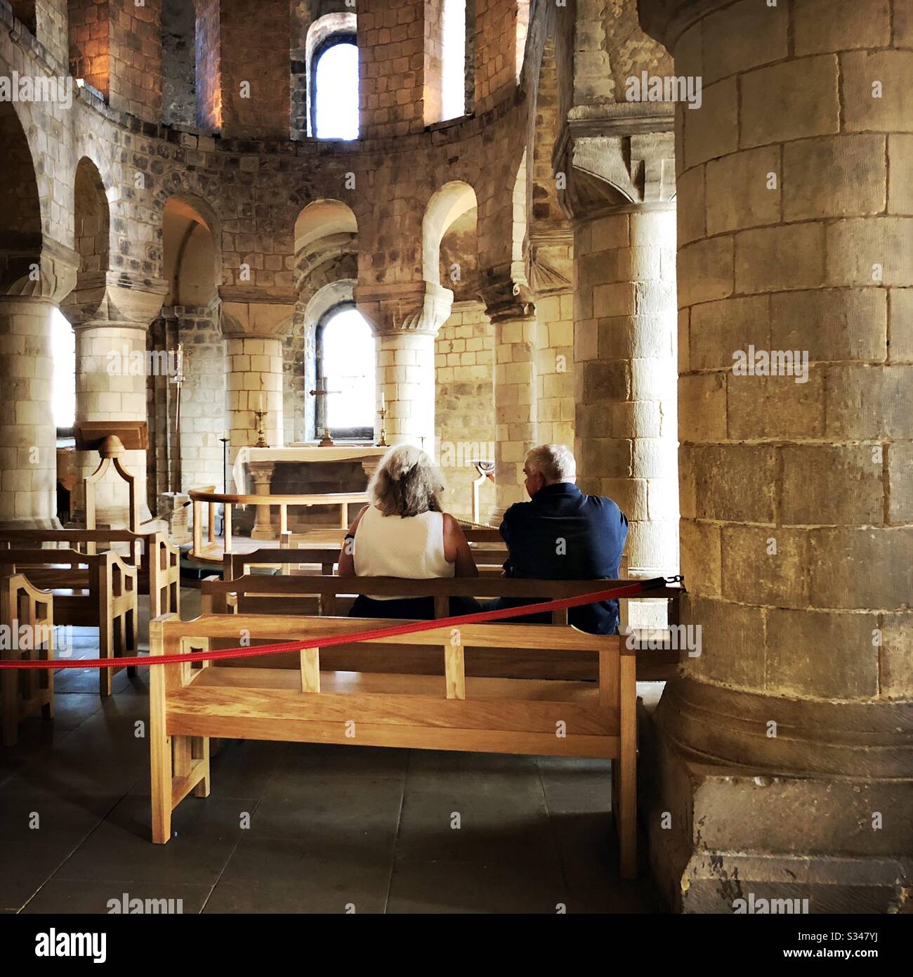 An elder couple are seen sitting on pews in St John’s Chapel within the White Tower, Tower of London. UNESCO World Heritage Site. - Smartphone Captured Stock Image