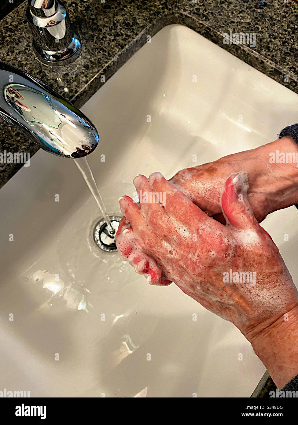 Woman washing her hands in a sink - Smartphone Captured Stock Image