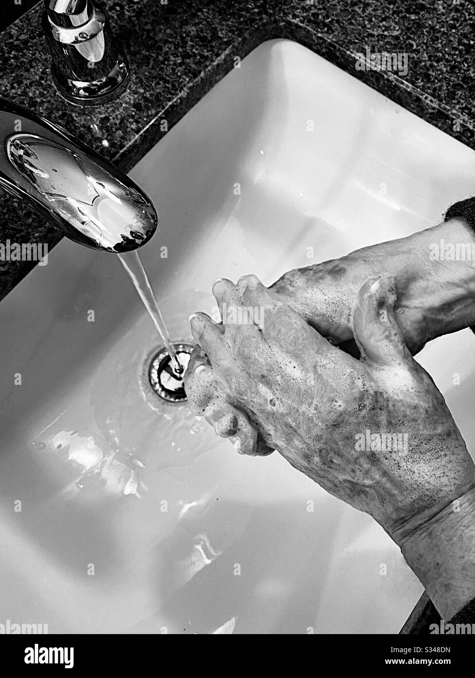 Woman washing her hands in a sink - Smartphone Captured Stock Image