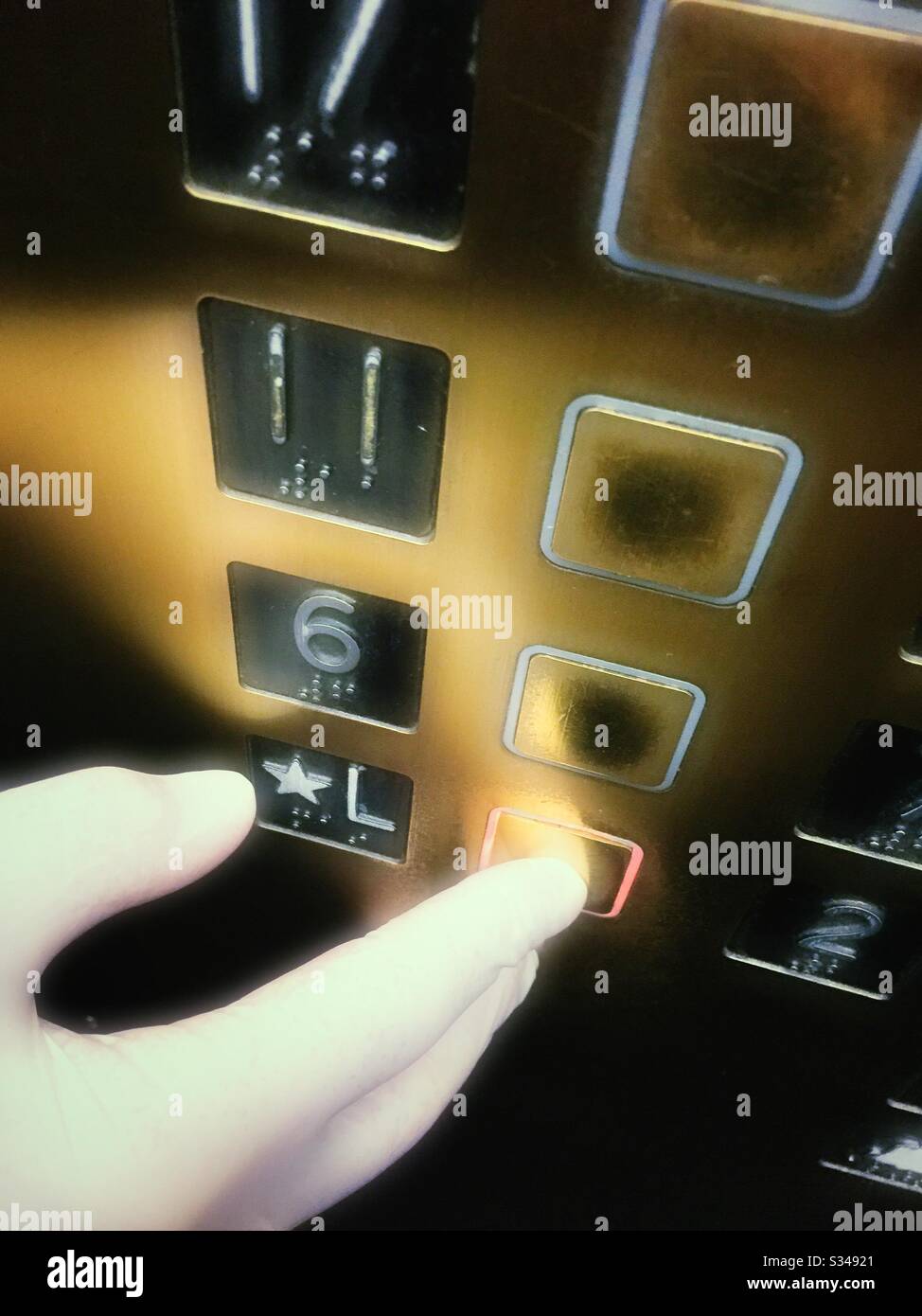 A man pushing an elevator button wearing a latex glove during the coronavirus pandemic, USA - Smartphone Captured Stock Image