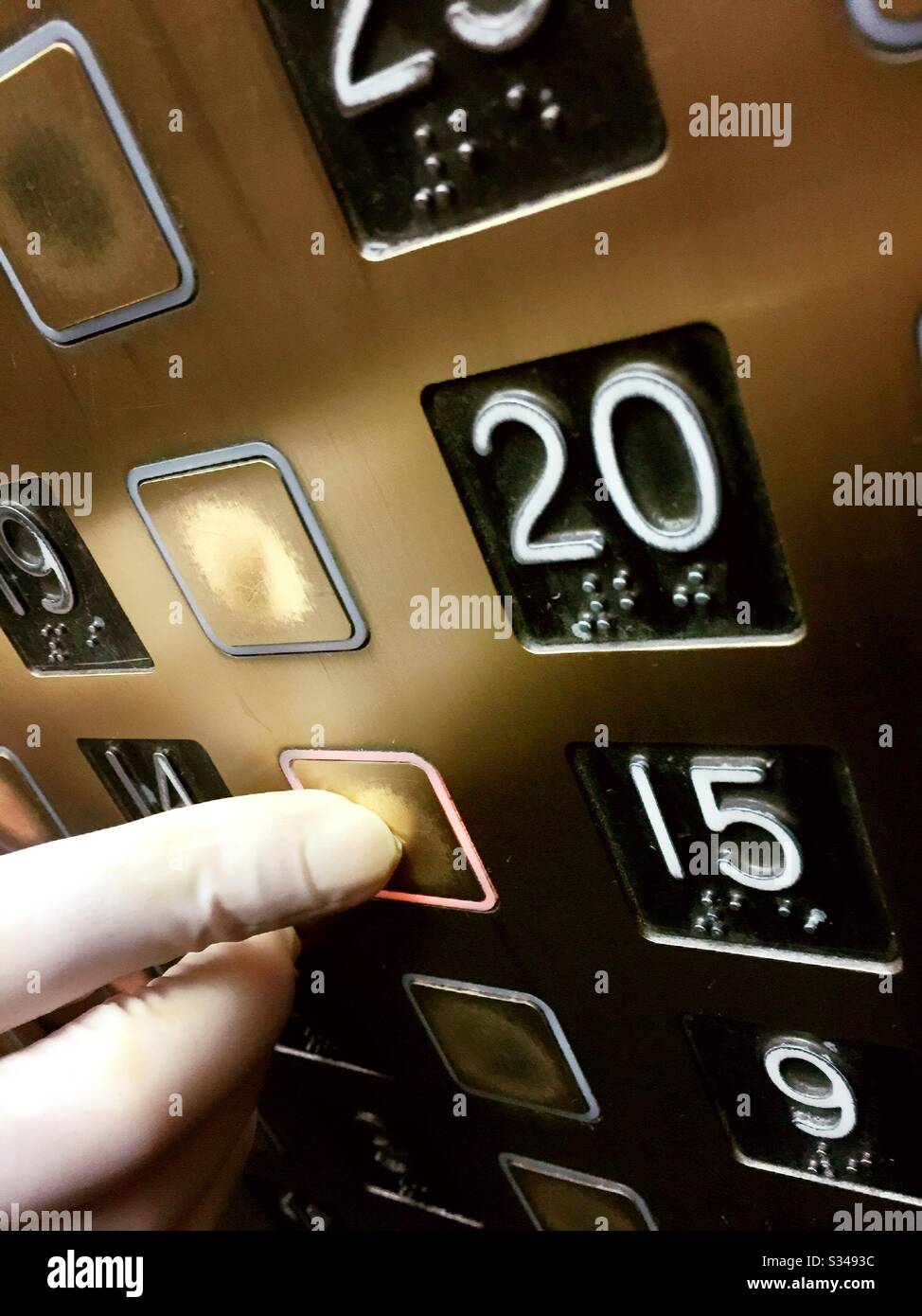 Covid-19 prevention being practiced by a person wearing a latex glove  pushing an elevator button to prevent the spread of the coronavirus, USA - Smartphone Captured Stock Image