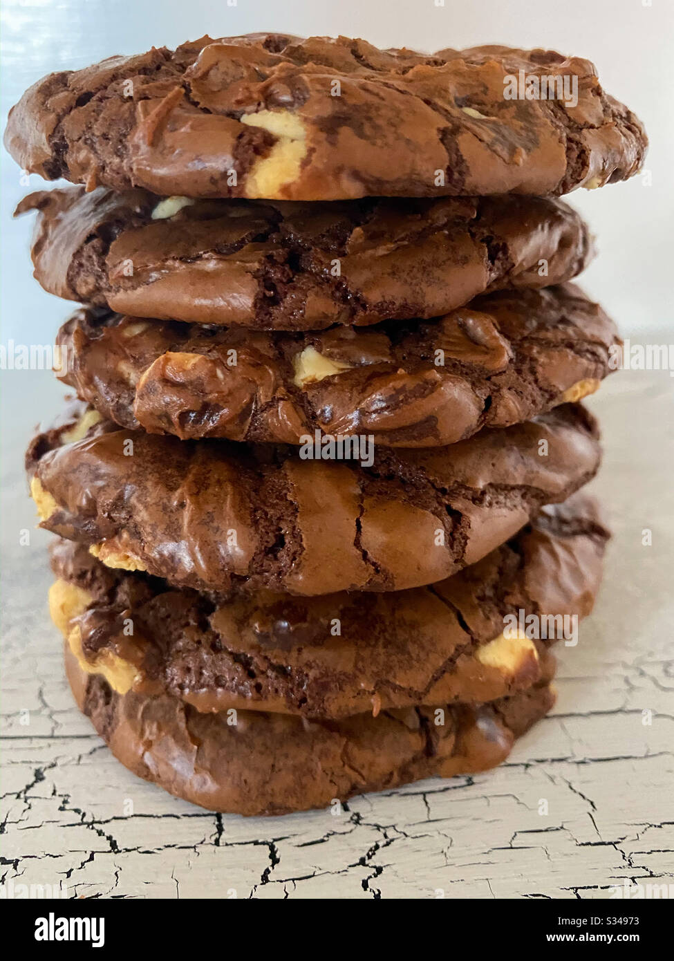 Vertical stack of chocolate white chocolate chip cookies on a black and white crackle surface - Smartphone Captured Stock Image