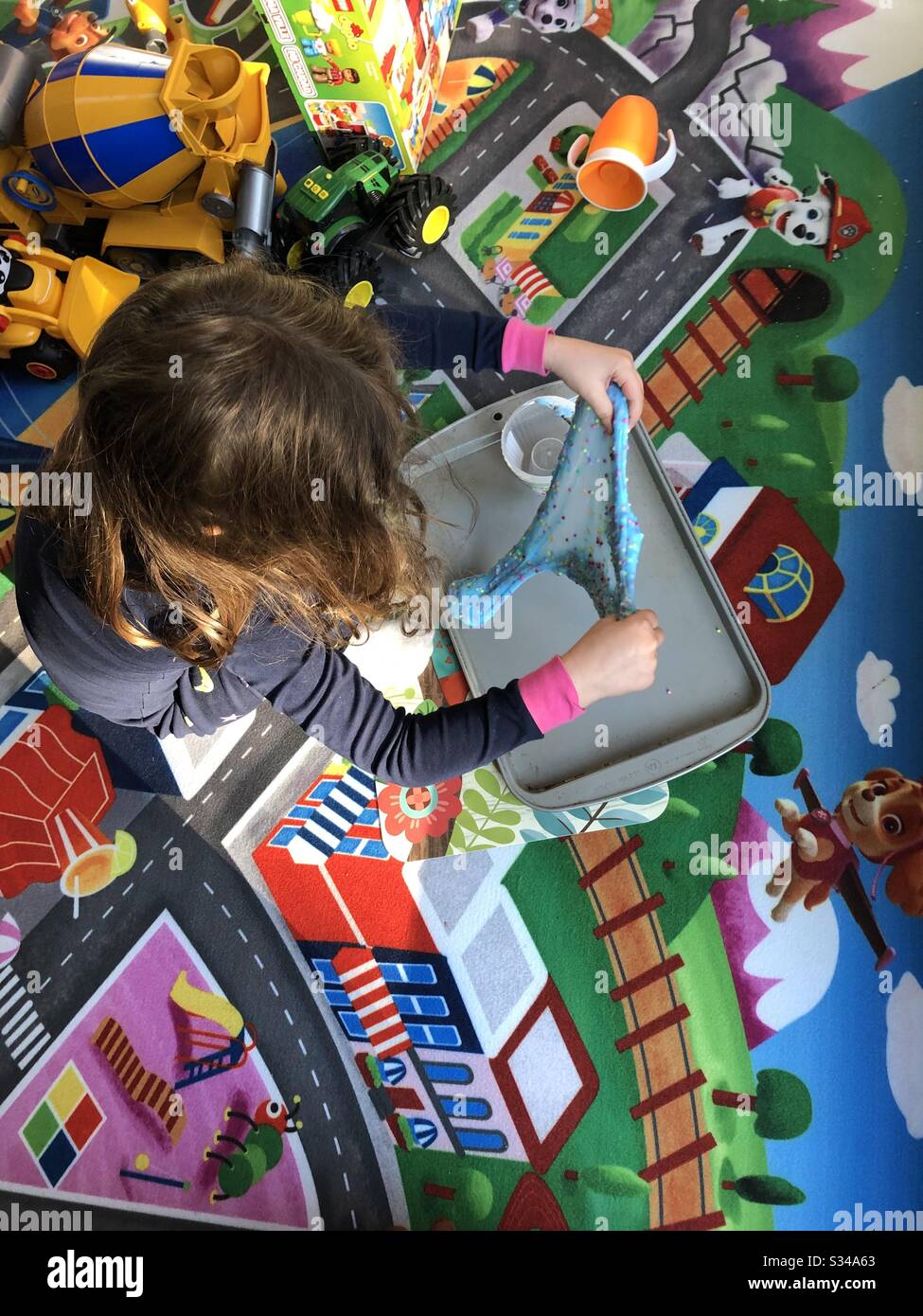 Six-year-old girl playing with the popular toy called Slime on a colorful play mat. - Smartphone Captured Stock Image