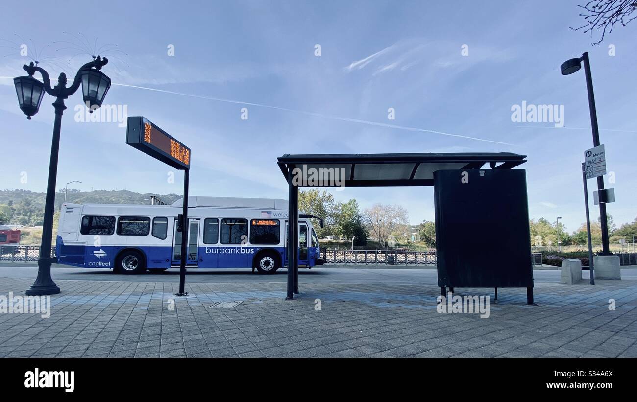 LOS ANGELES, CA, MAR 2020: blue and white Burbank Bus driving next to stop at Universal City, near LA Metro station - Smartphone Captured Stock Image