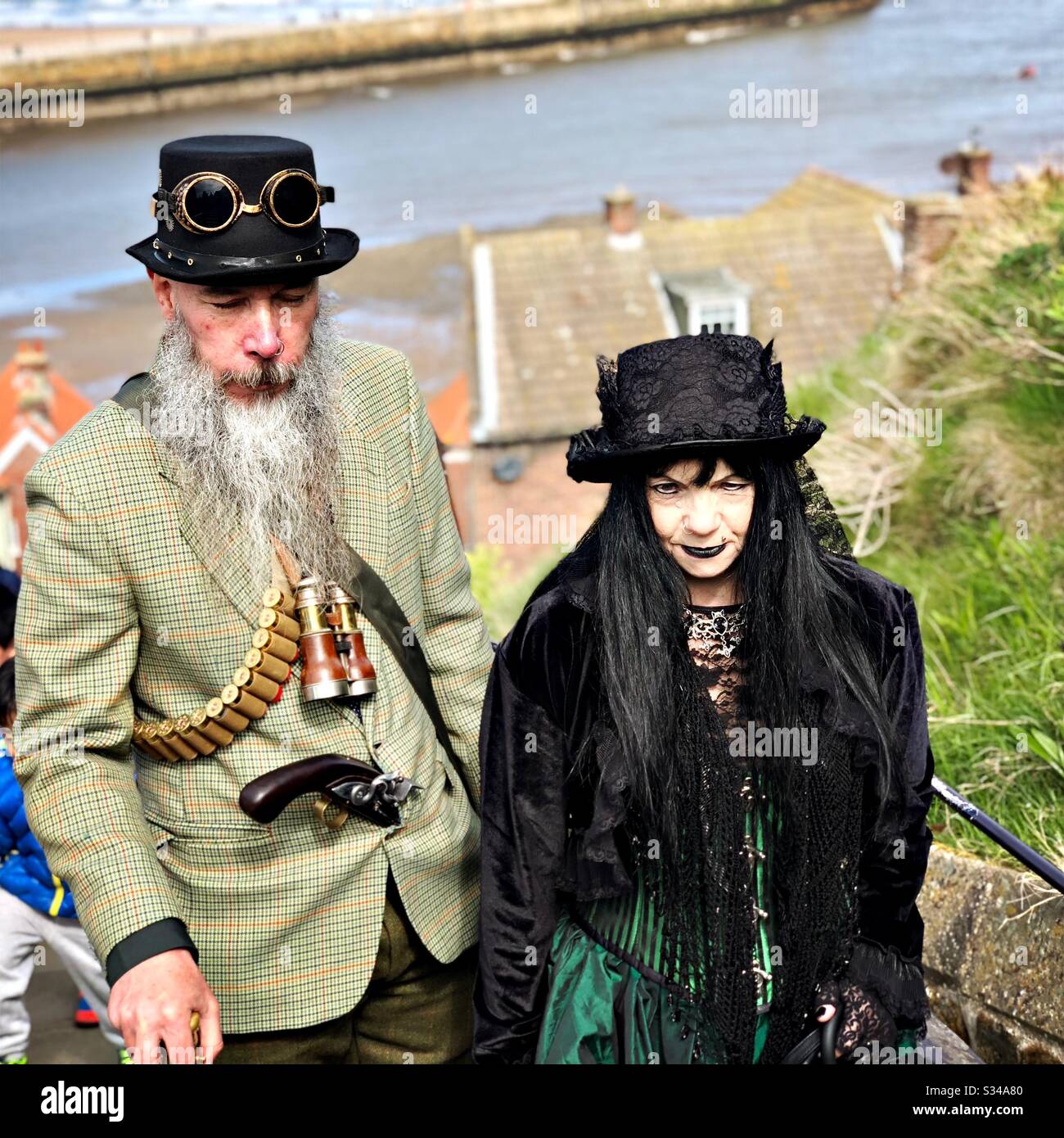 People in creative costumes during a cosplay event. Whitby Goth Weekend. Steampunk man and goth woman - Smartphone Captured Stock Image
