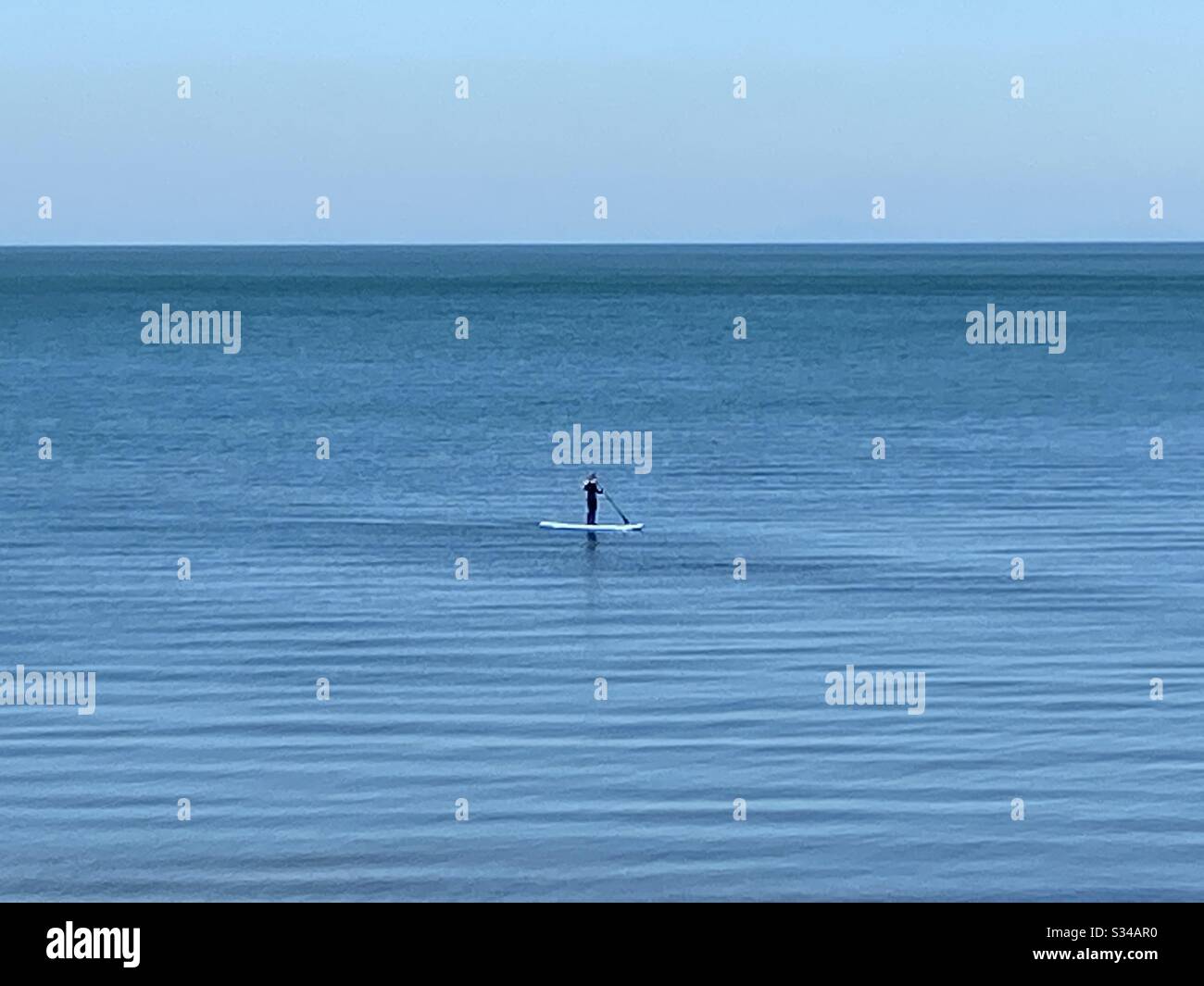 Aberystwyth, West Wales, UK. Sunday 22nd March 2020. News: A warm and sunny afternoon, a person is seen paddleboarding on Mothering Sunday, the sea is calm and peaceful.©️Rose Voon/Alamy Live News Stock Photo