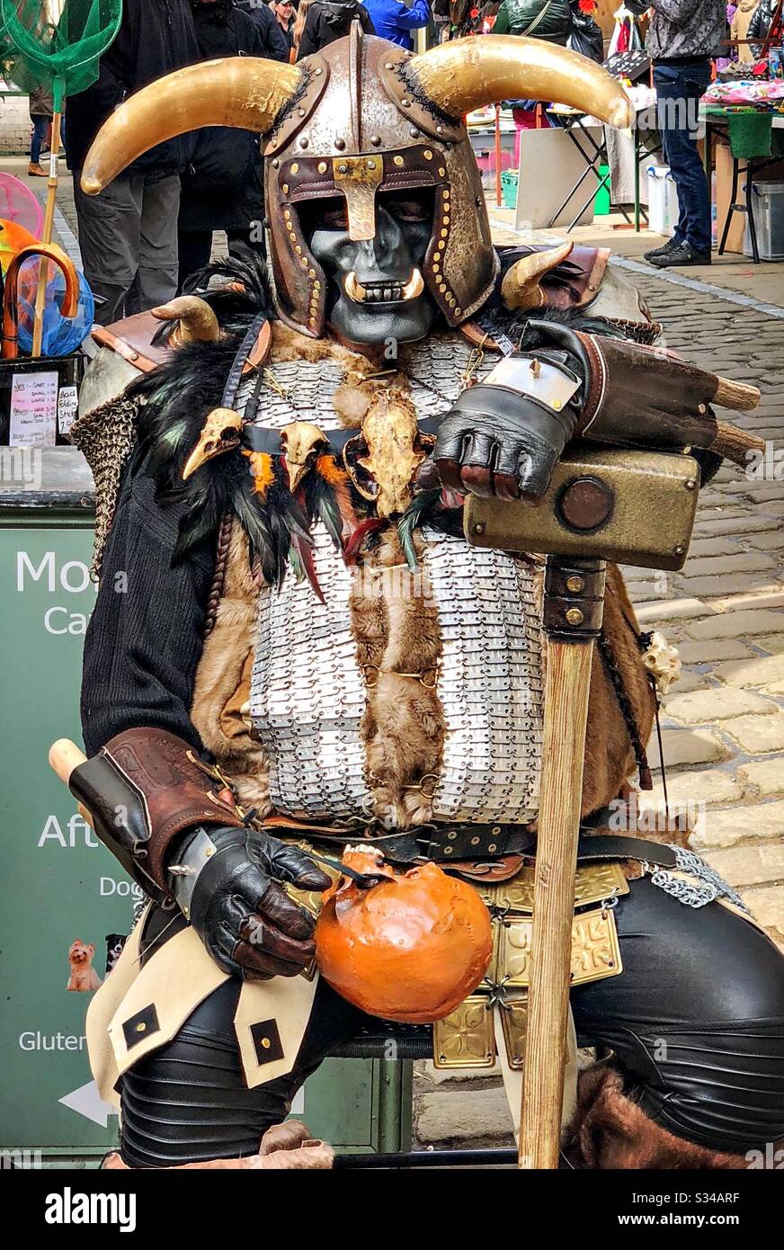 Person in a creative costume during a cosplay event. Whitby Goth Weekend. Man wears steampunk troll outfit with horns and hammer - Smartphone Captured Stock Image