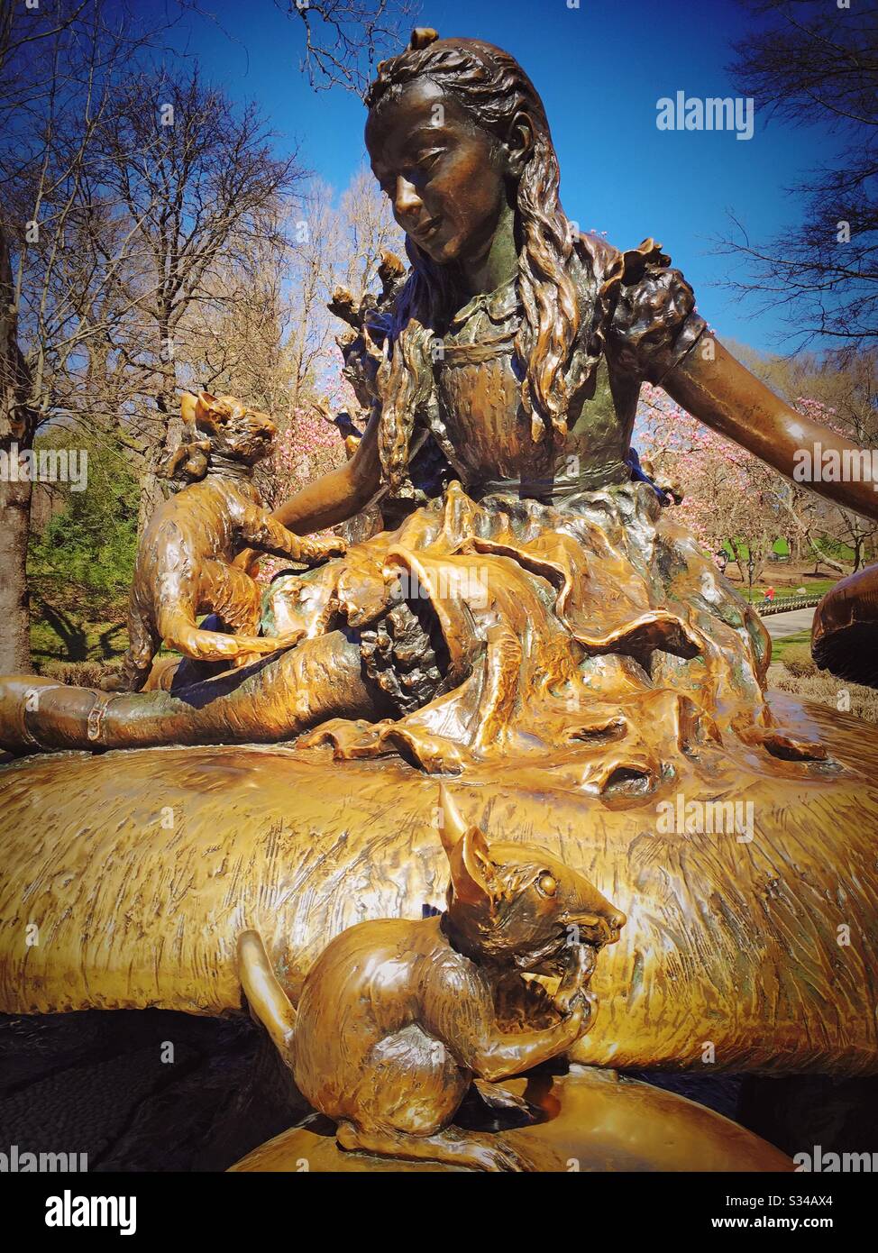 The statue of Alice in wonderland is a bronze sculpture in central park near the toy boat pond as seen in the early spring, NYC, USA Stock Photo