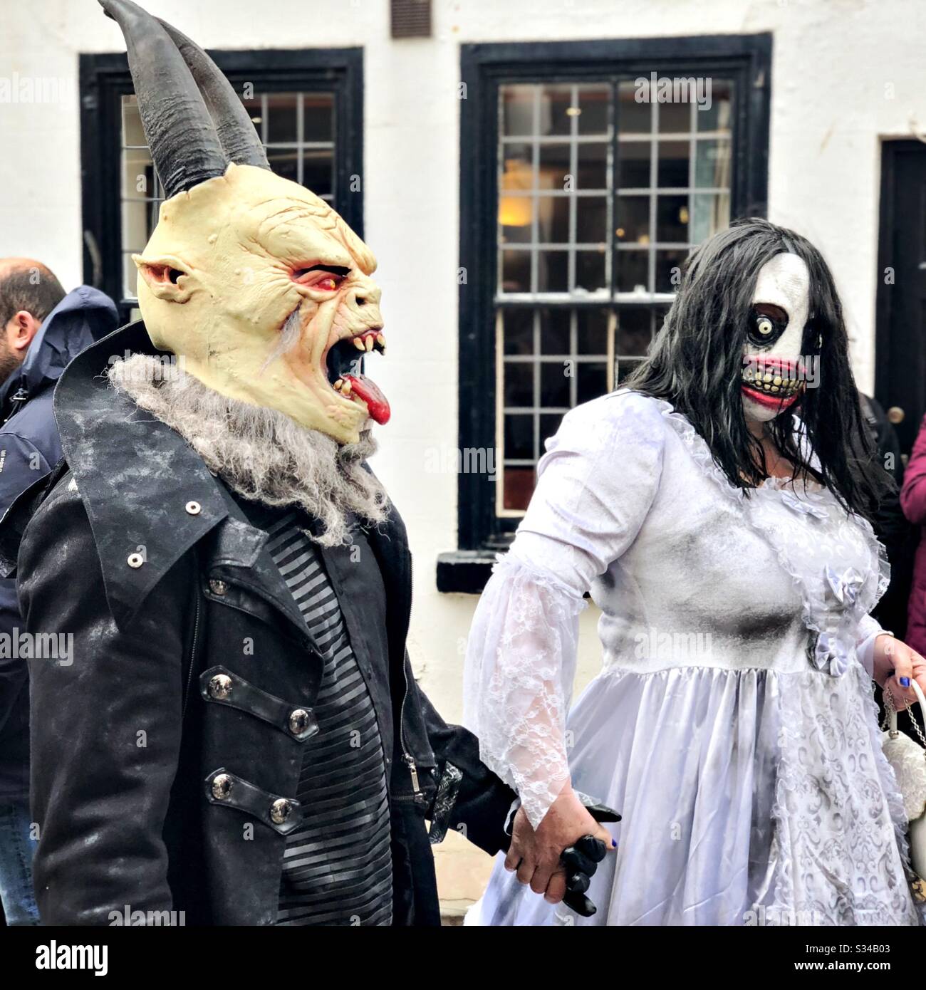 People in creative costumes during a cosplay event. Whitby Goth Weekend. Monster man and woman couple in street, horror outfits and masks - Smartphone Captured Stock Image