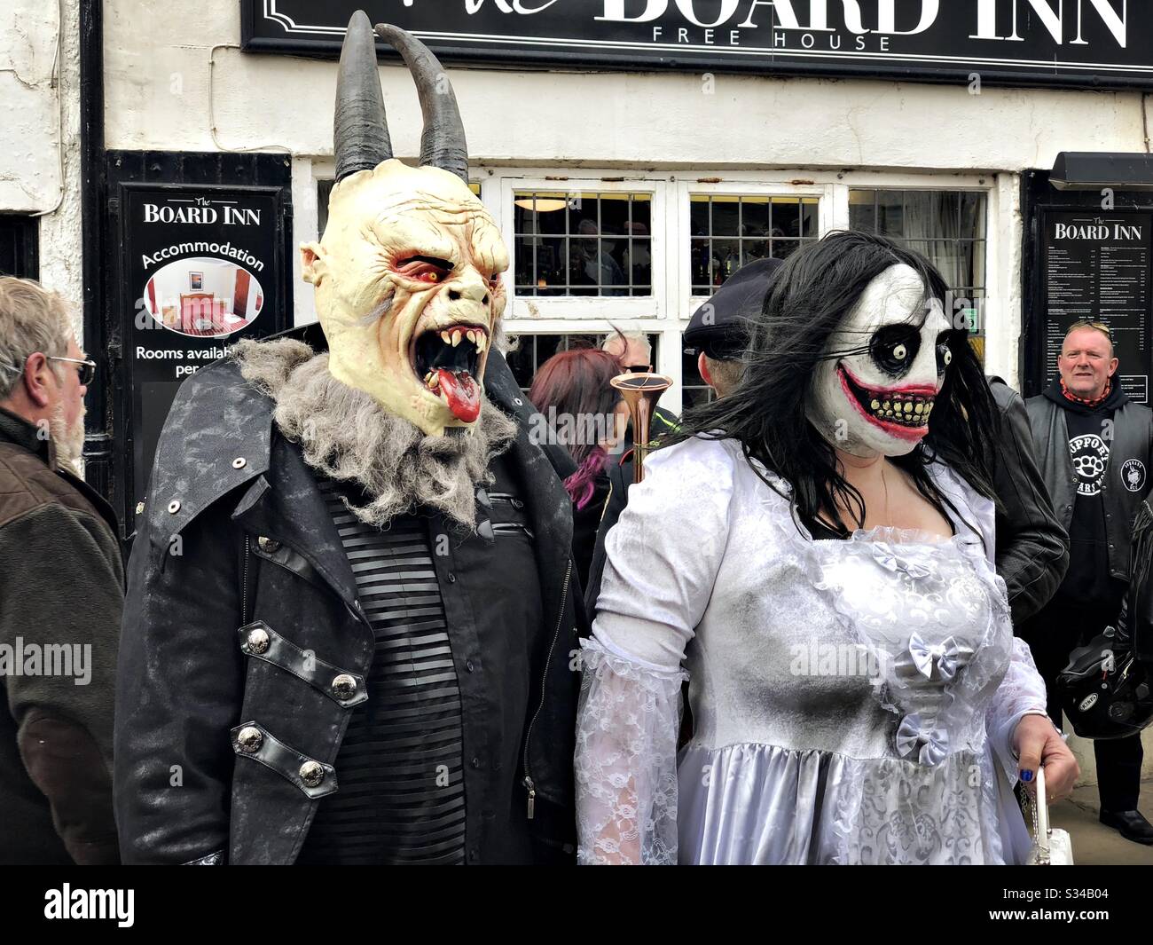 People in creative costumes during a cosplay event. Whitby Goth Weekend. Monster man and woman couple in street, horror outfits and masks - Smartphone Captured Stock Image