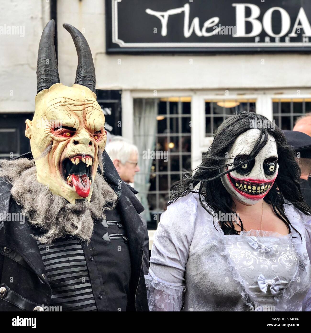 People in creative costumes during a cosplay event. Whitby Goth Weekend. Monster man and woman couple in street, horror outfits and masks - Smartphone Captured Stock Image