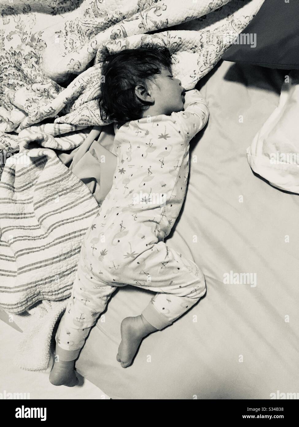 Toddler baby boy stretched out on blankets in pajamas sleeping. - Smartphone Captured Stock Image