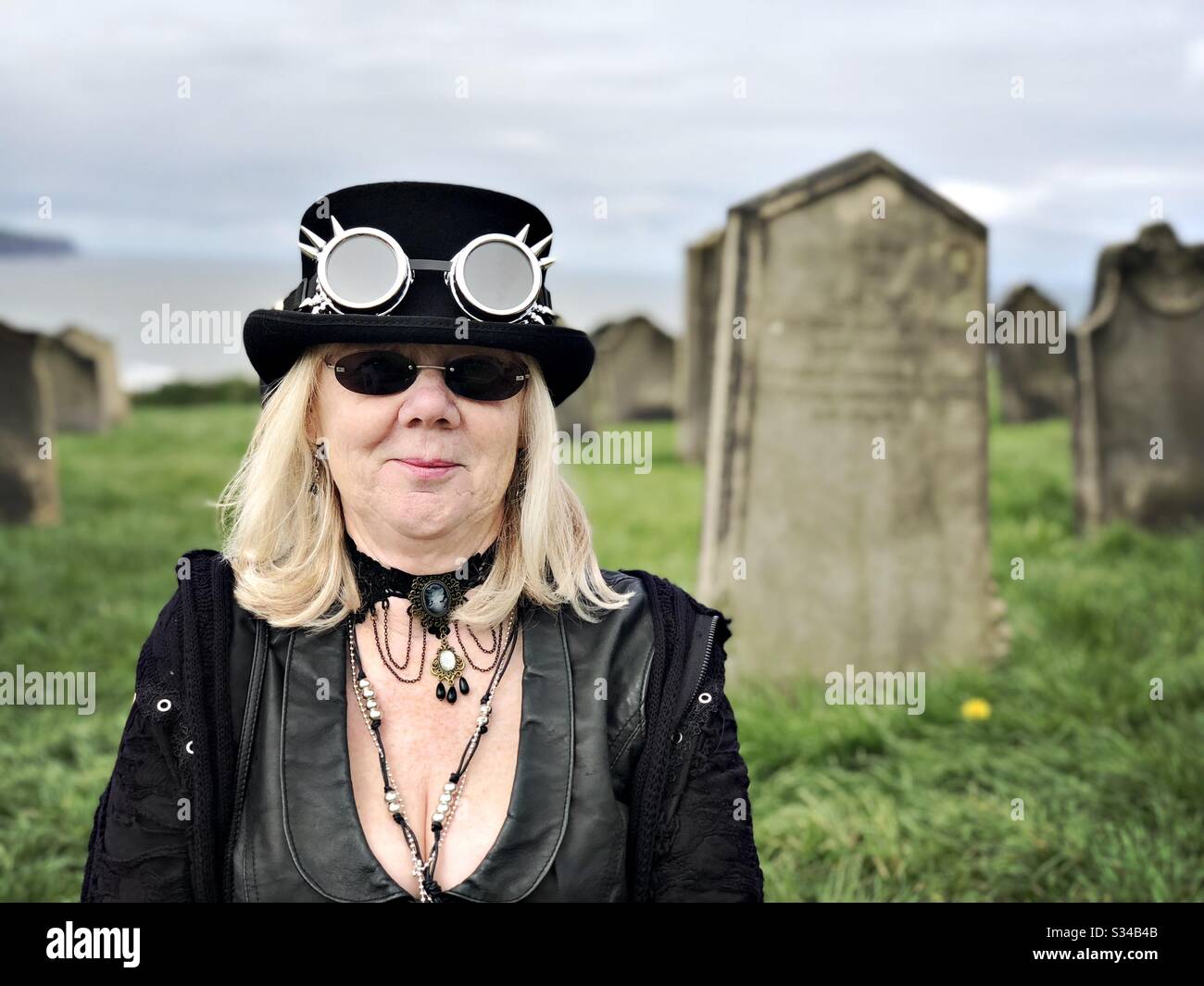 Person in a creative costume during a cosplay event. Whitby Goth Weekend. Steampunk goth woman in cemetery - Smartphone Captured Stock Image