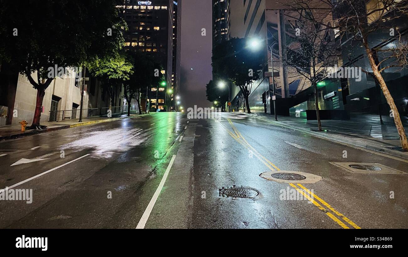 LOS ANGELES, CA, MAR 2020: night view with wet streets, looking up Olive St towards offices in Financial District of Downtown - Smartphone Captured Stock Image