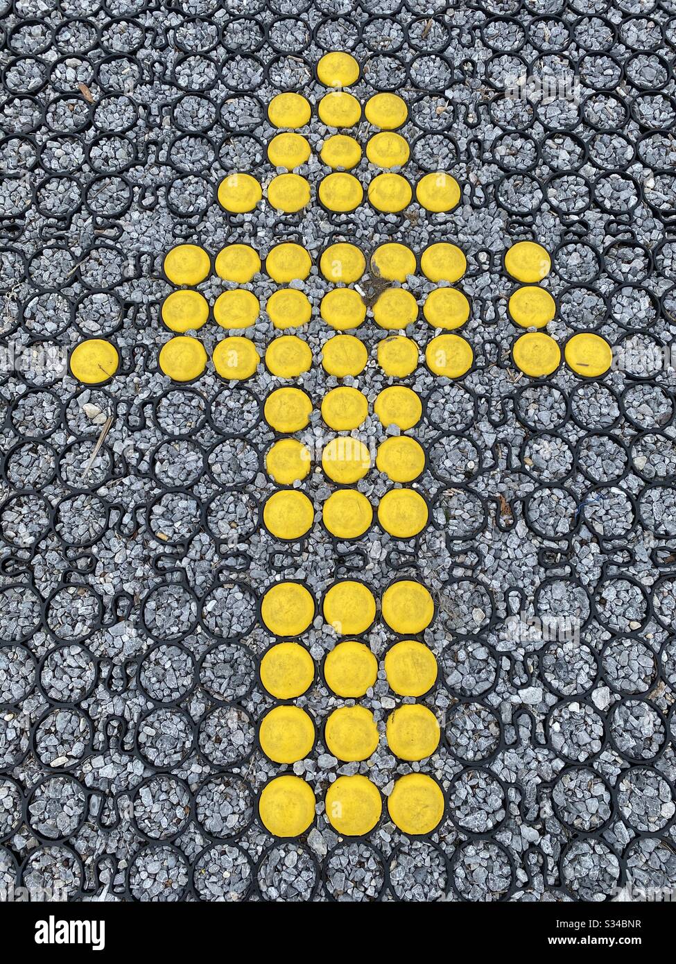 Bright yellow entrance arrow on textured surface on the street - Smartphone Captured Stock Image