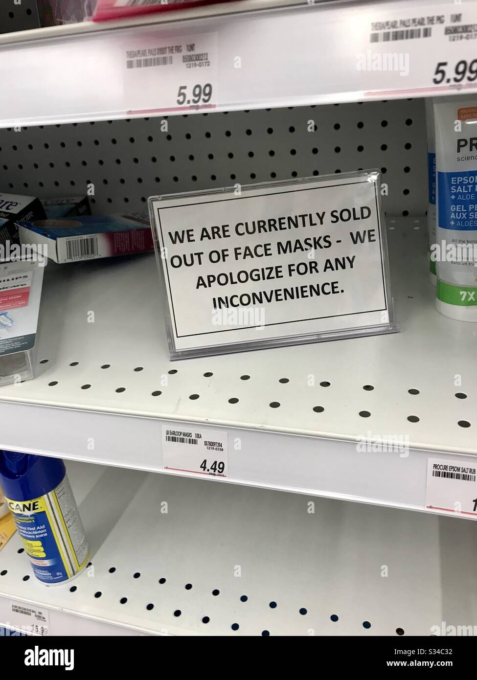 Burnaby, BC, Canada. March 13, 2020.  Sign in a Shopper’s Drug Mart store stating they are sold out of face masks.  Empty shelves where people have bought supplies for the Covid-19 pandemic. - Smartphone Captured Stock Image