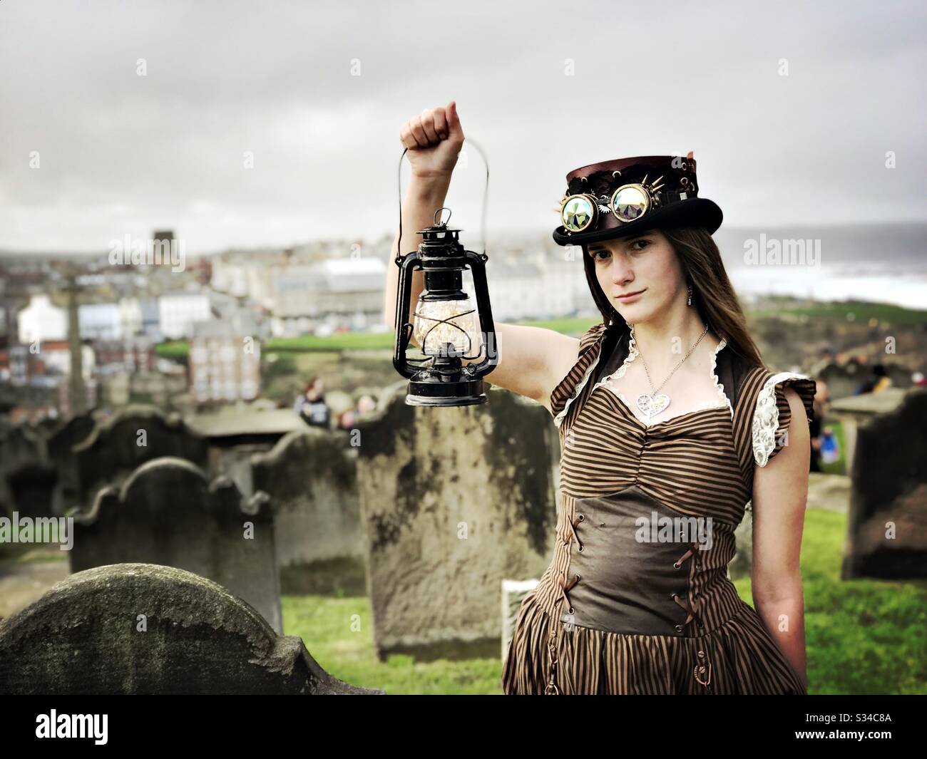 Person in a creative costume during a cosplay event. Whitby Goth Weekend. Steampunk girl with lantern in graveyard - Smartphone Captured Stock Image