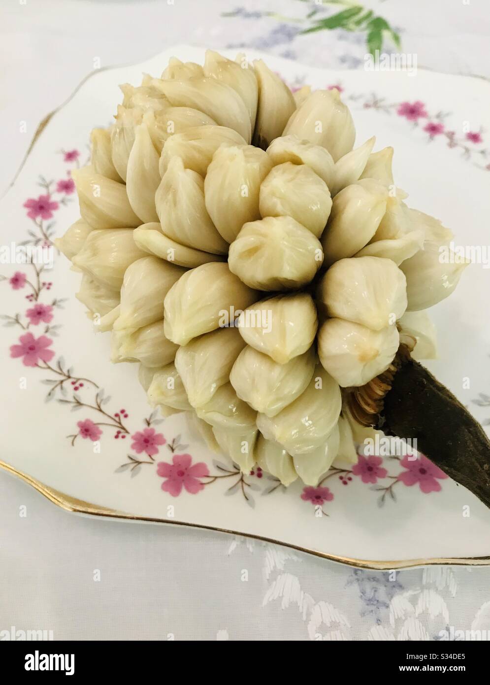 A bouquet of marang fruit served on an English fine bone China.  Such a skill to peel the entire fruit and serve it whole! Exotic tropical fruit in full elegance. Stock Photo