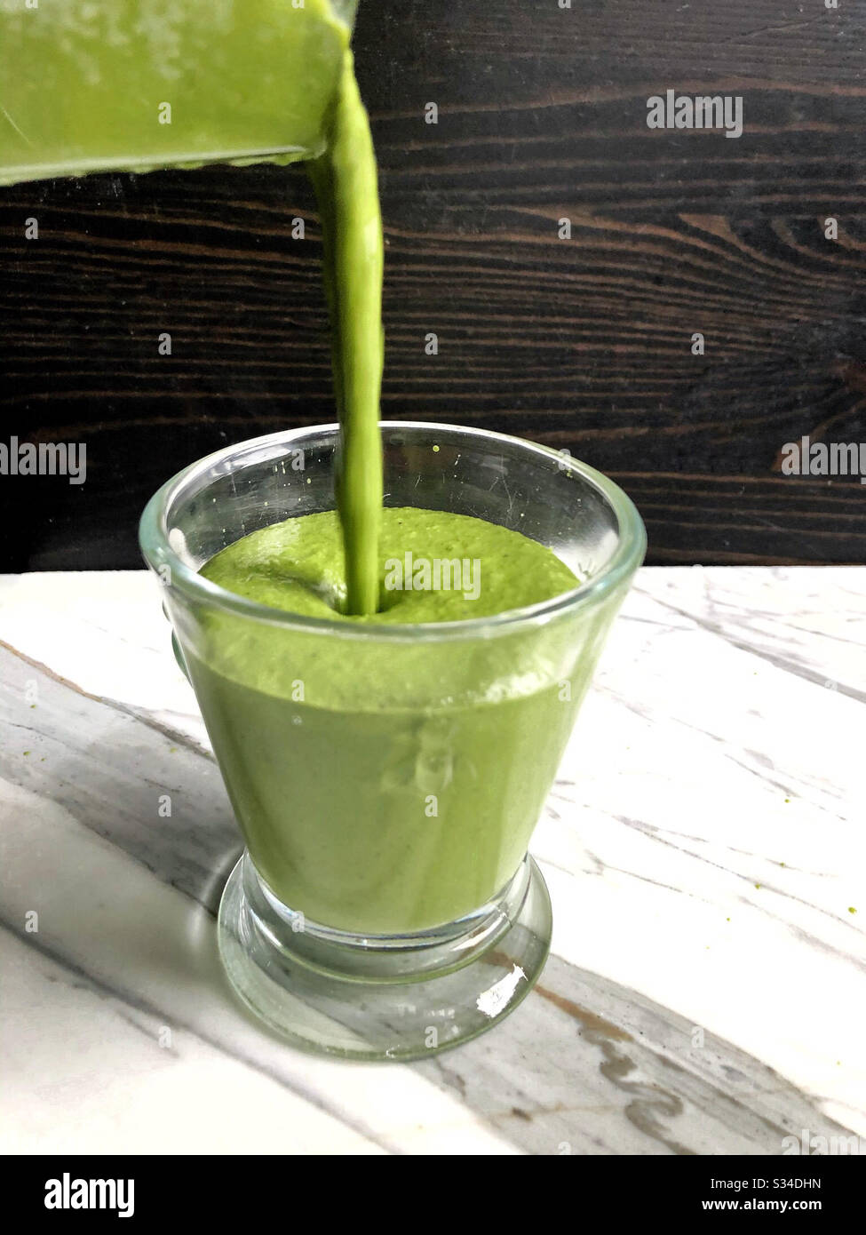Green smoothie made in a blender at home with avocado, green banana, ginger, coconut oil, and spinach. - Smartphone Captured Stock Image