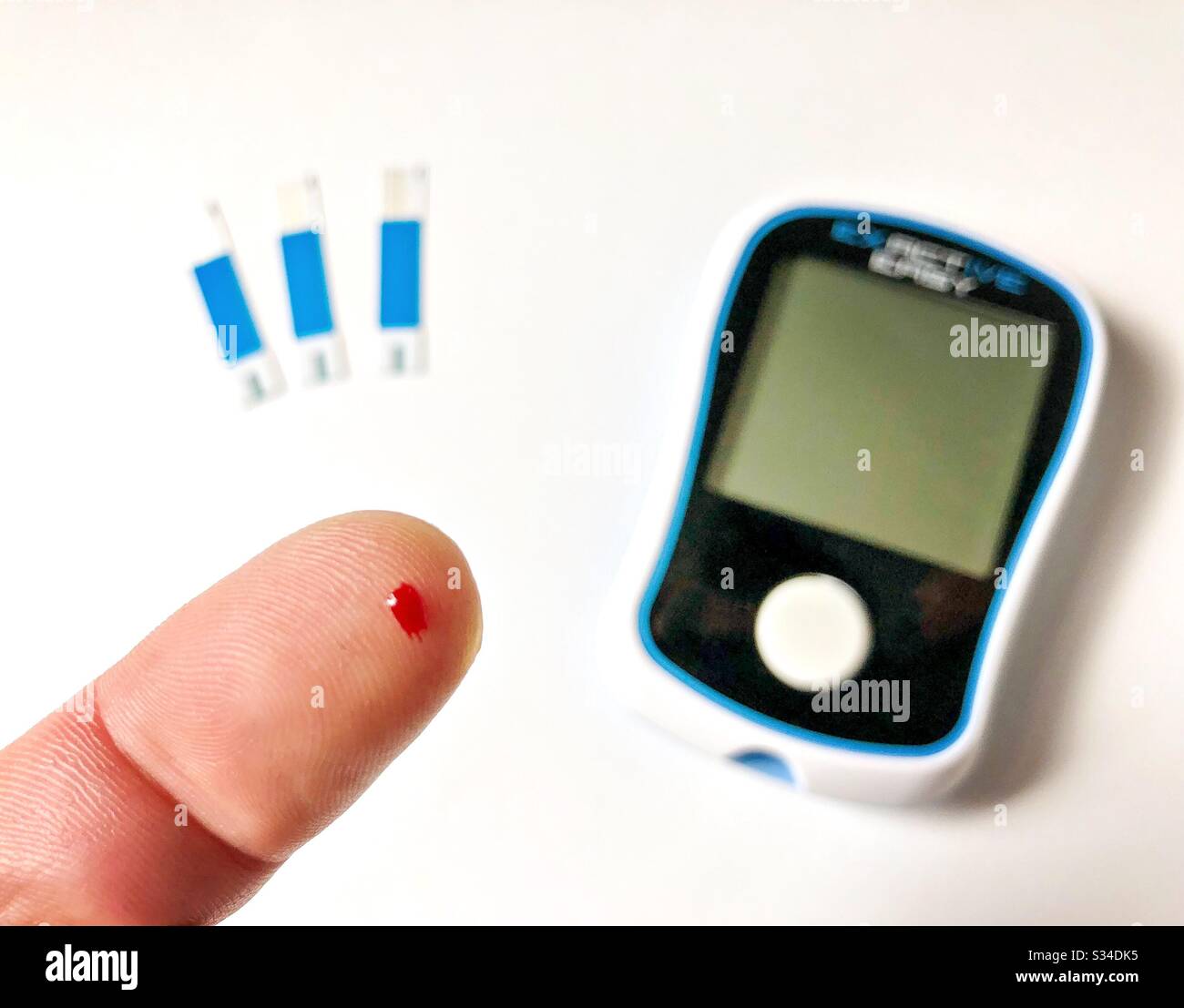 A close up shot on the finger of a diabetic person using a finger prick test. With spot of blood