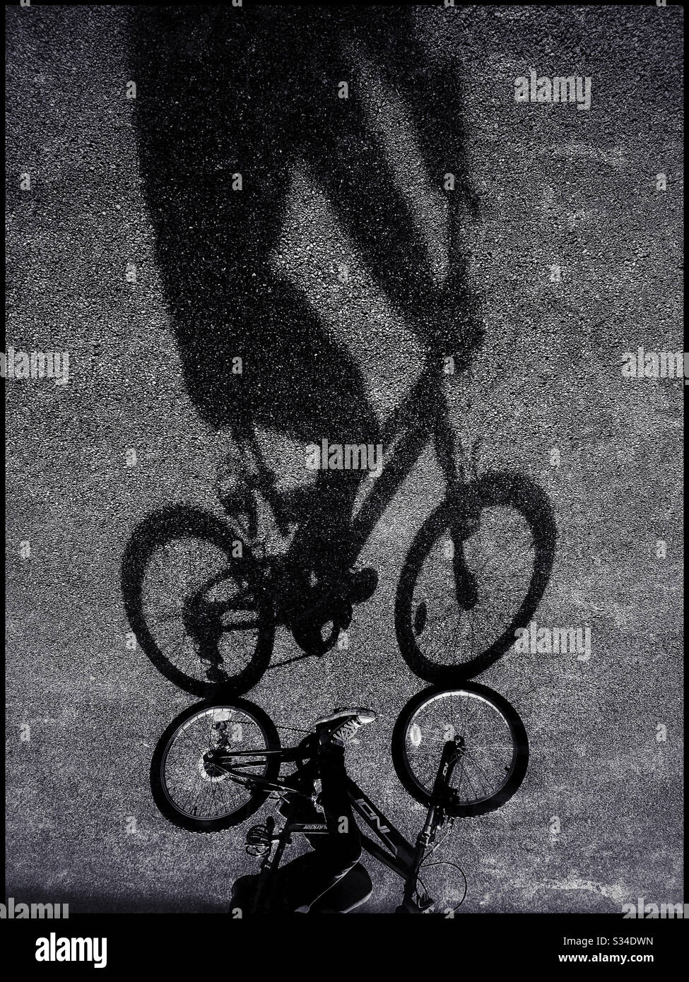 An upside down, gravity defying image of a child cycling. Bright sunshine provides interesting shadows! Photo Credit - © COLIN HOSKINS. - Smartphone Captured Stock Image